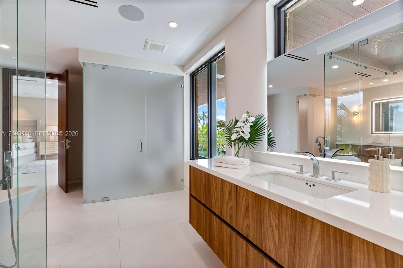 Built-in wood-paneled sauna featuring a glass-door entrance, accompanied by a walk-in shower with a mosaic-tiled accent wall, glass enclosure, transom