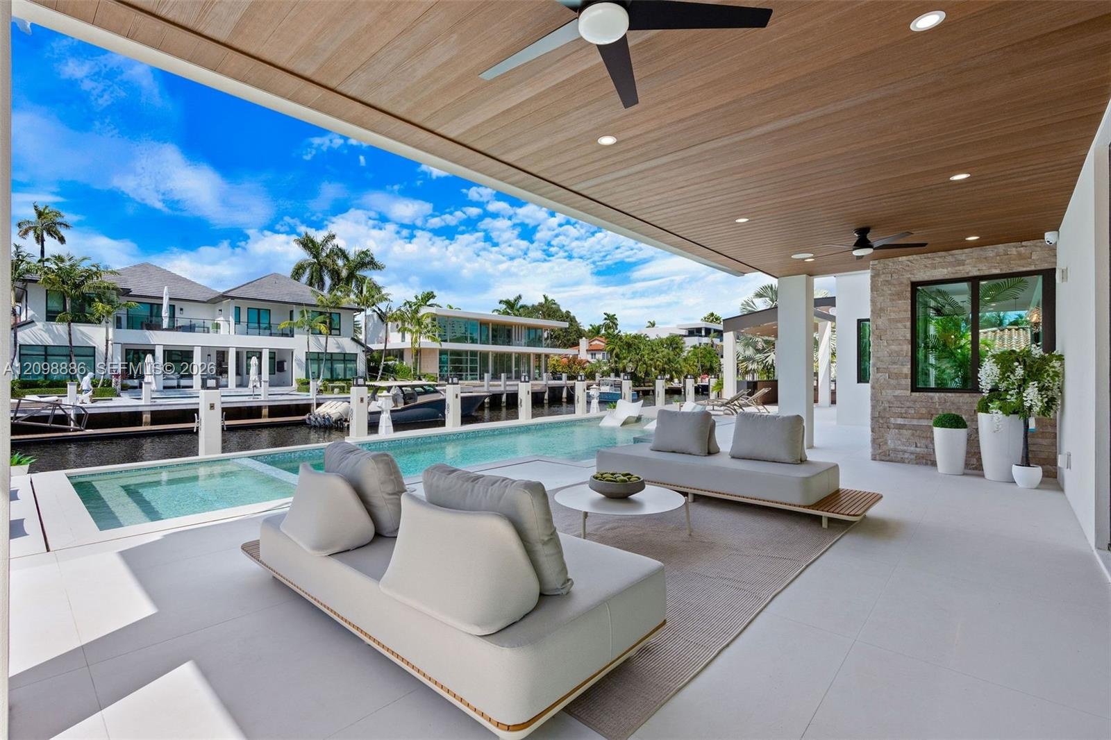 Covered patio featuring a wood-plank ceiling, recessed lighting, and dual ceiling fans, complete with a stone-accented wall and a custom pool borderin