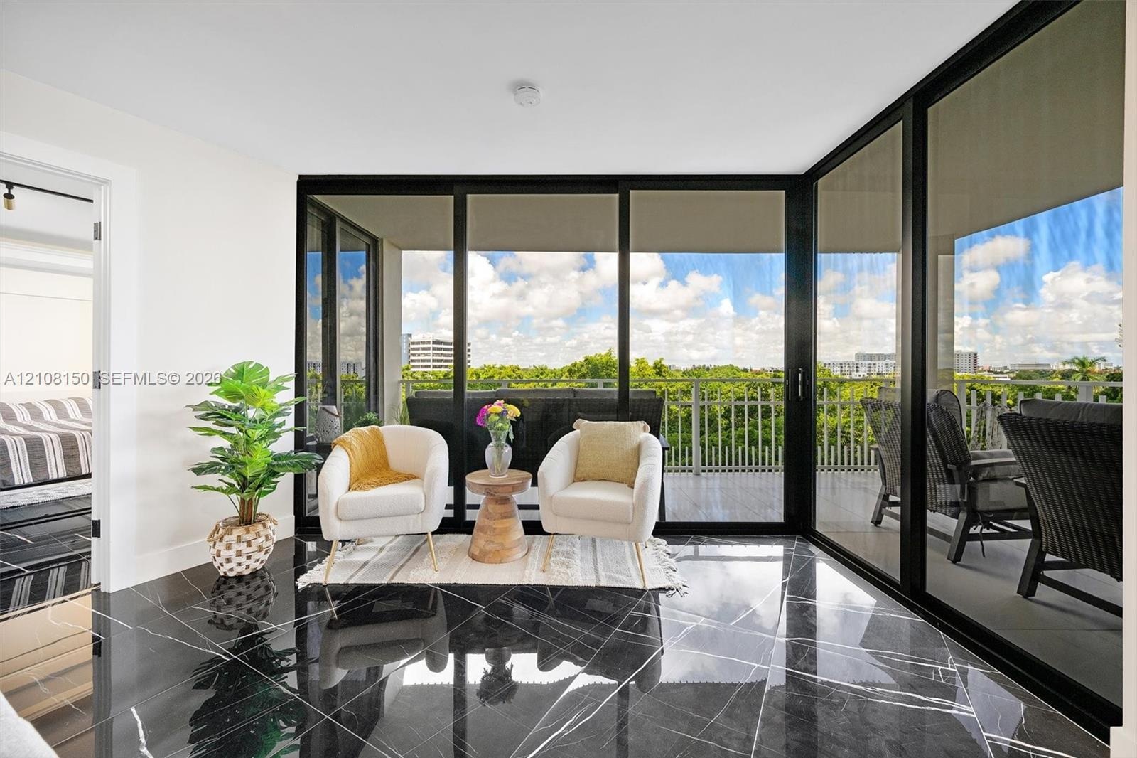 Polished dark stone tile flooring, expansive floor-to-ceiling glass walls, and a private outdoor balcony with metal railing
