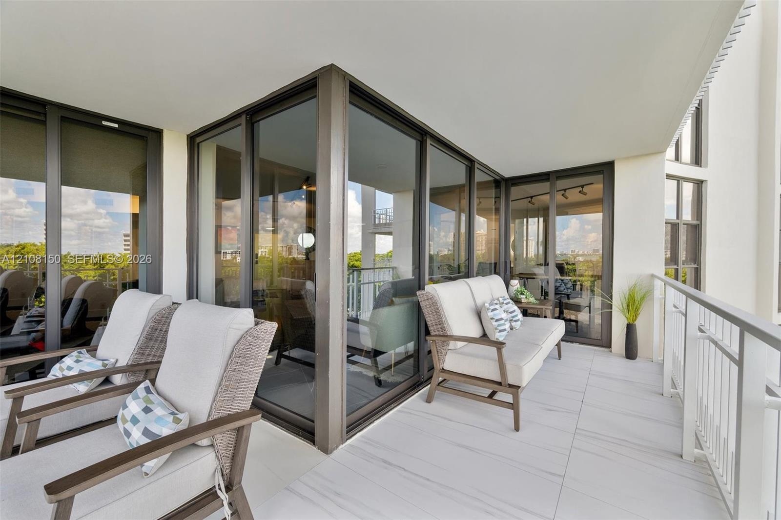 Covered balcony featuring oversized tile flooring, full-height glass-paneled sliding doors, and a metal railing