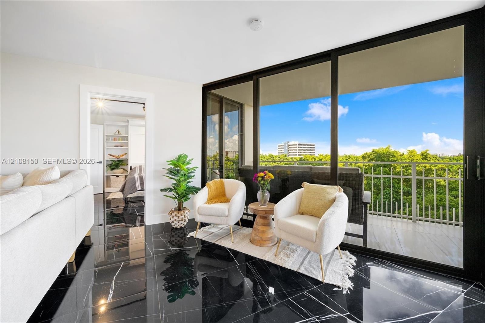 Polished black flooring with white veining, expansive floor-to-ceiling sliding glass doors, and a private balcony with metal railing