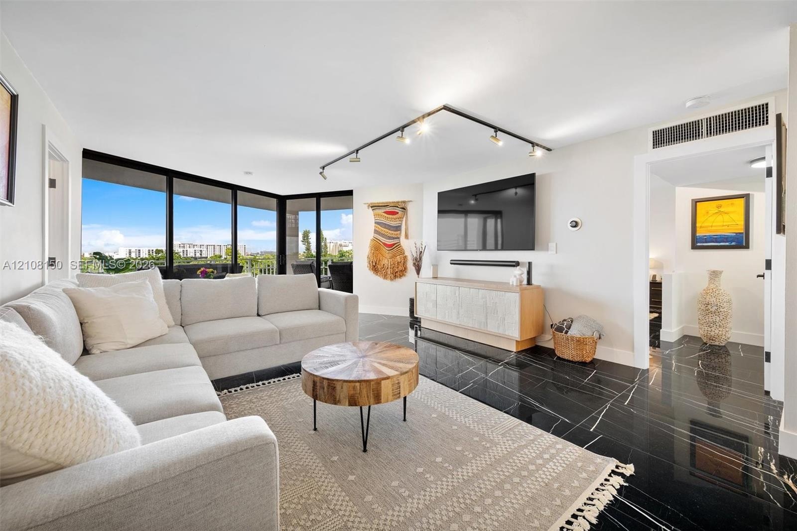 Living area featuring floor-to-ceiling windows, black polished stone-finish flooring, and adjustable track lighting