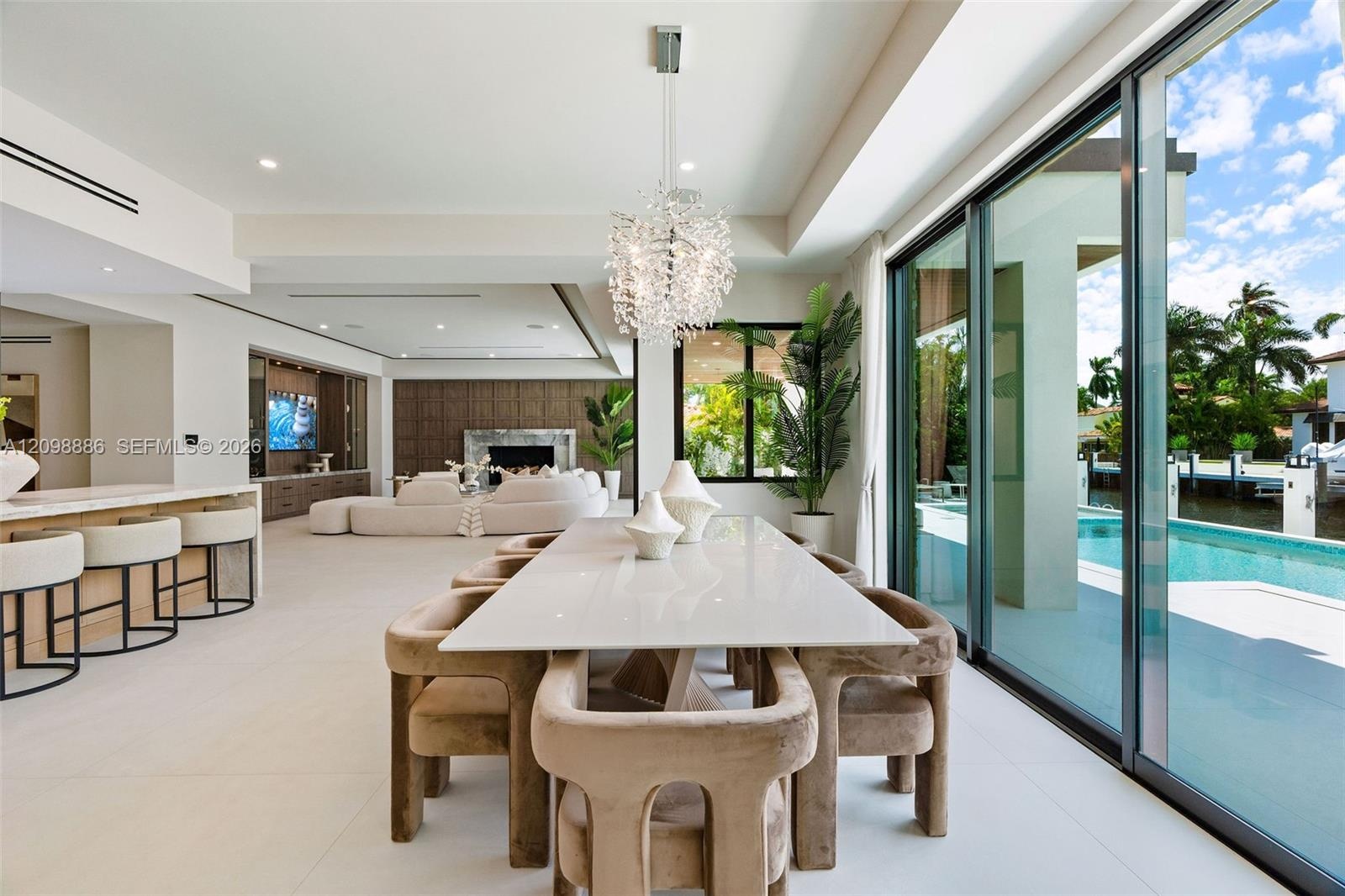 Open-concept interior featuring large-format tile flooring, a statement crystal chandelier, built-in cabinetry, a fireplace with stone surround, and f