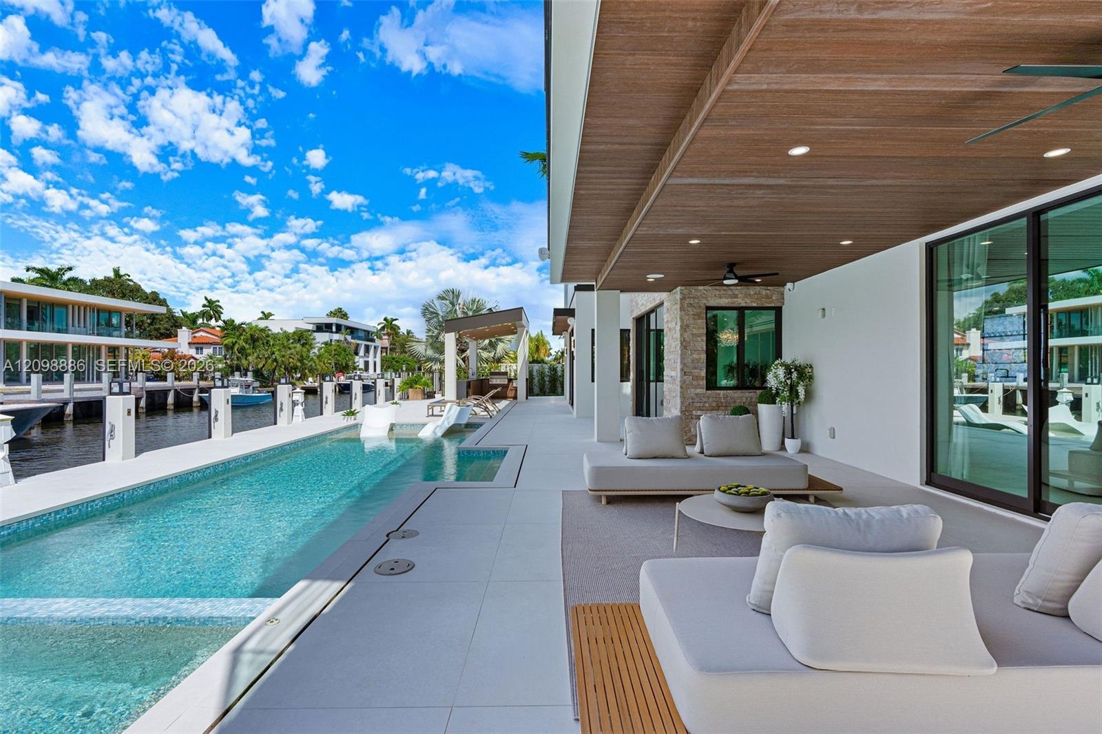 Covered patio featuring a wood-plank ceiling with recessed lighting, integrated lap pool with tiled interior, stacked stone wall accent, and expansive