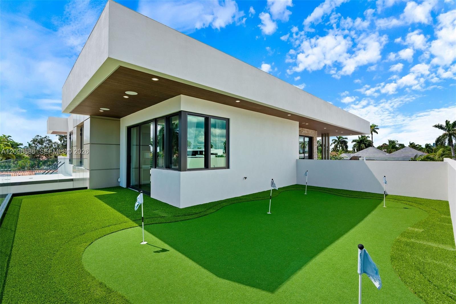 Contemporary rooftop terrace featuring a multi-hole putting green, synthetic turf surfacing, flat-roof architecture, recessed ceiling lighting, and fl