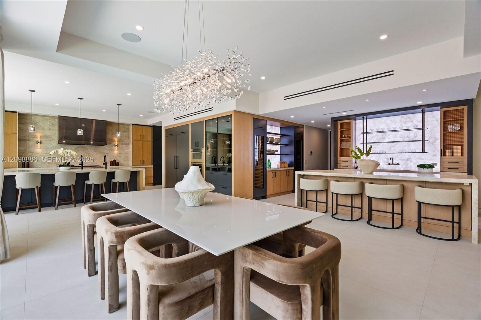 Gourmet kitchen featuring quartz countertops, wood-finish cabinetry, a geometric crystal chandelier, integrated wine refrigeration, and large-format t