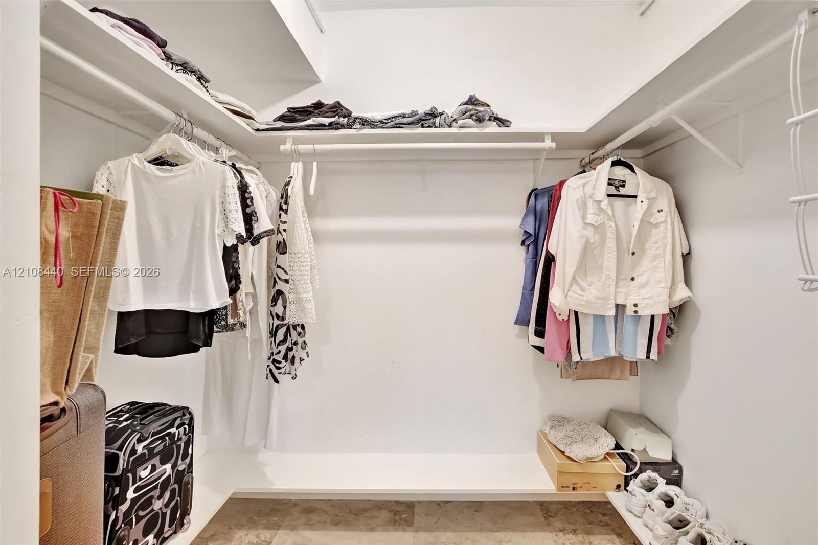 Walk-in closet featuring tiered shelving, integrated clothing rods, and tile flooring