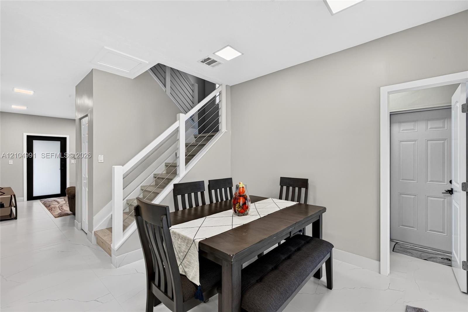 Staircase featuring a white handrail and horizontal wire balusters, light-toned large-format tile flooring, and recessed LED ceiling lighting