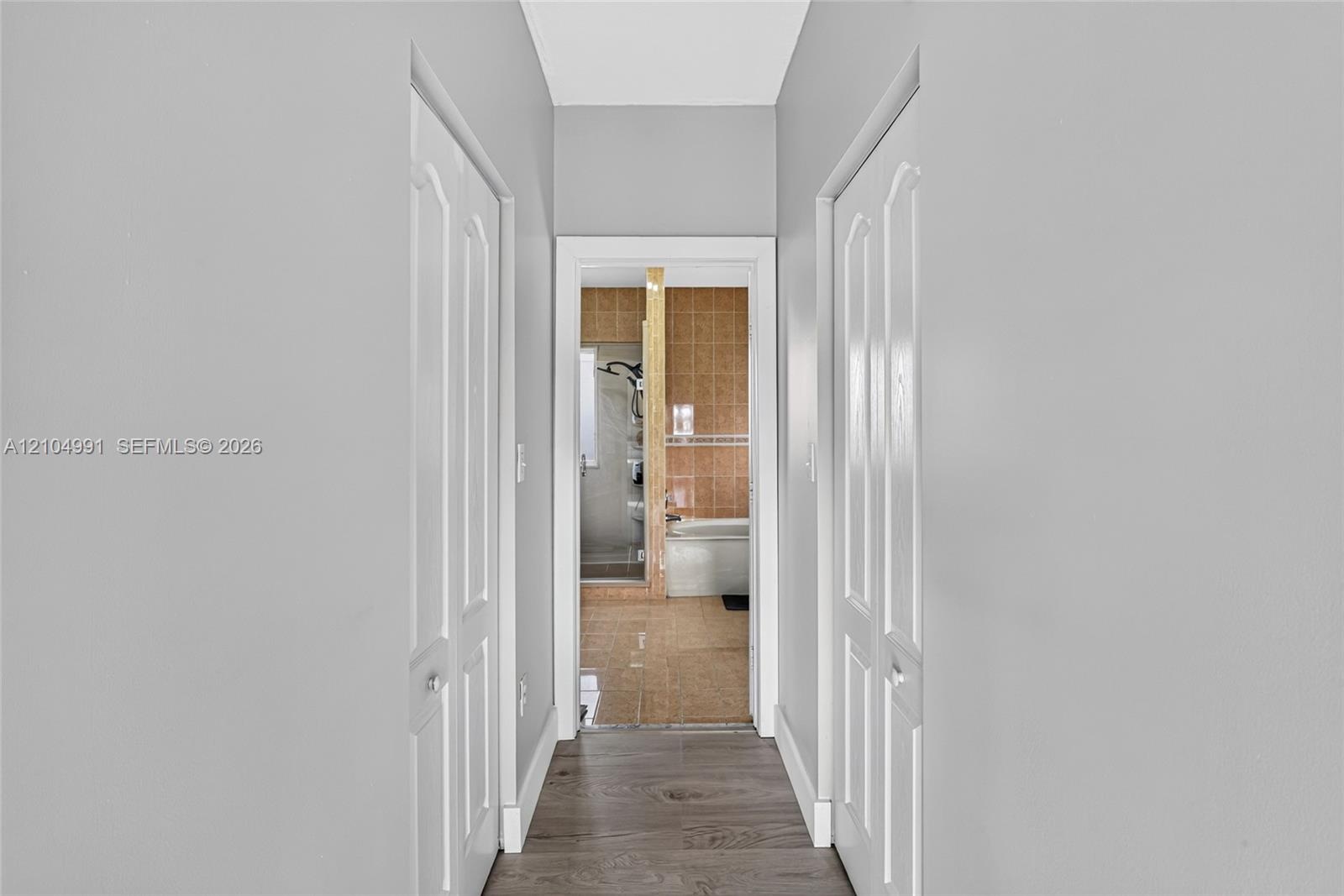 Hallway featuring wood-finish flooring and two sets of arched-panel bi-fold doors