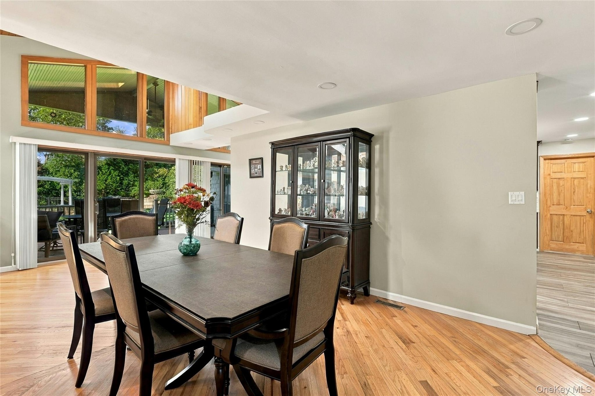 Open-concept dining area featuring wood-finish flooring, vaulted ceilings, expansive multi-pane windows, recessed lighting, and sliding glass doors