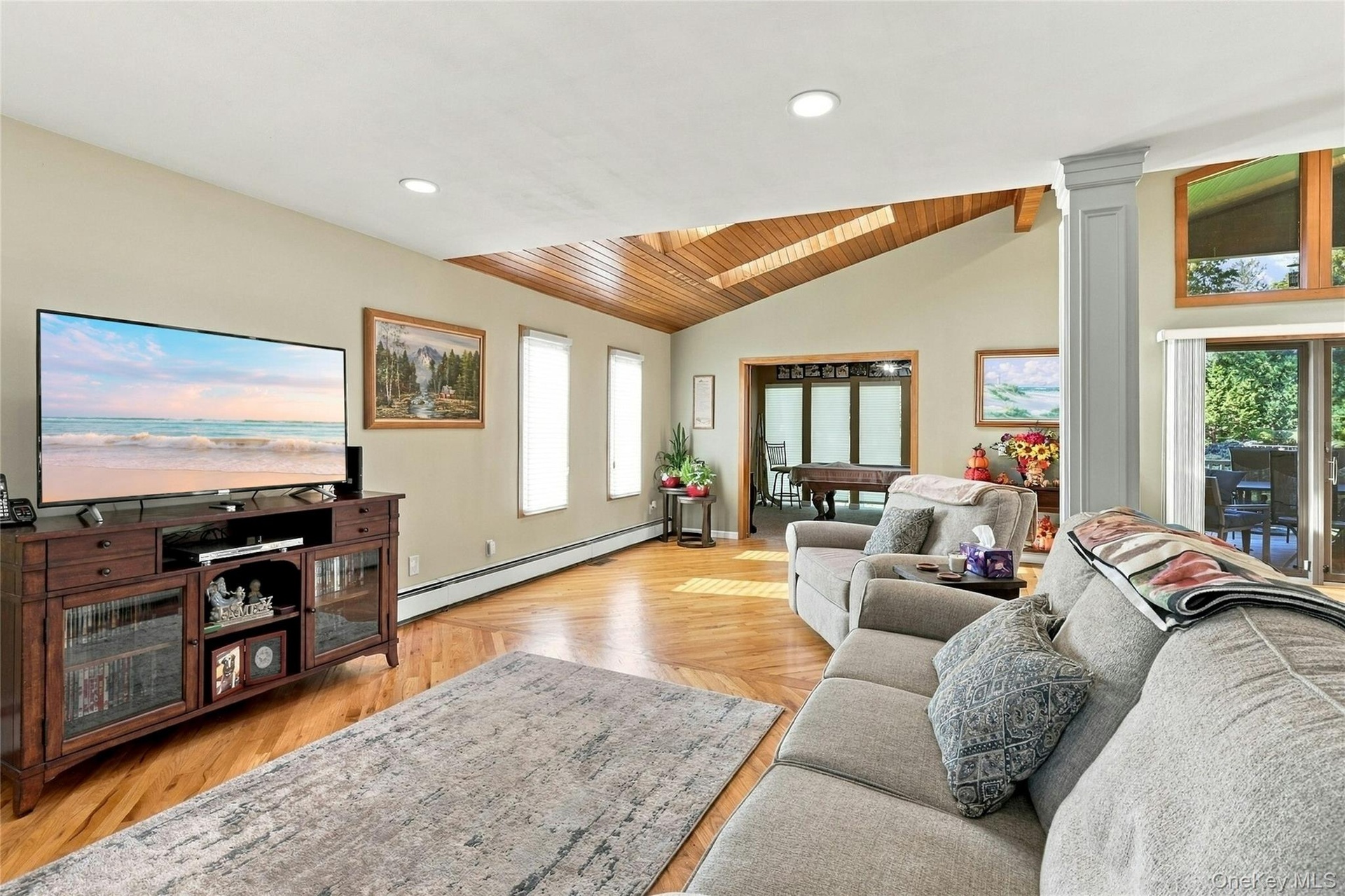 Living area featuring herringbone-patterned wood-finish flooring, vaulted wood-plank ceiling with skylights, recessed lighting, and sliding glass door
