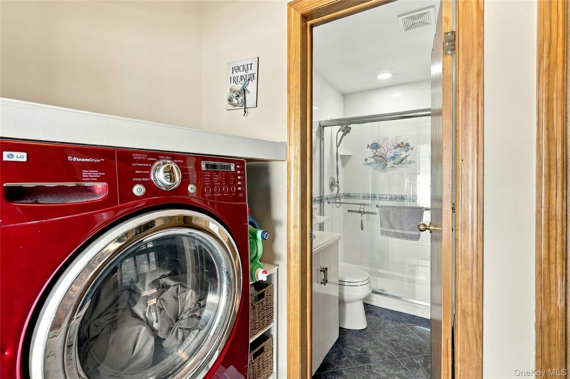 Laundry area featuring a built-in shelf and cabinetry, paired with a bathroom containing a walk-in shower with glass enclosure, tile surround, and dar