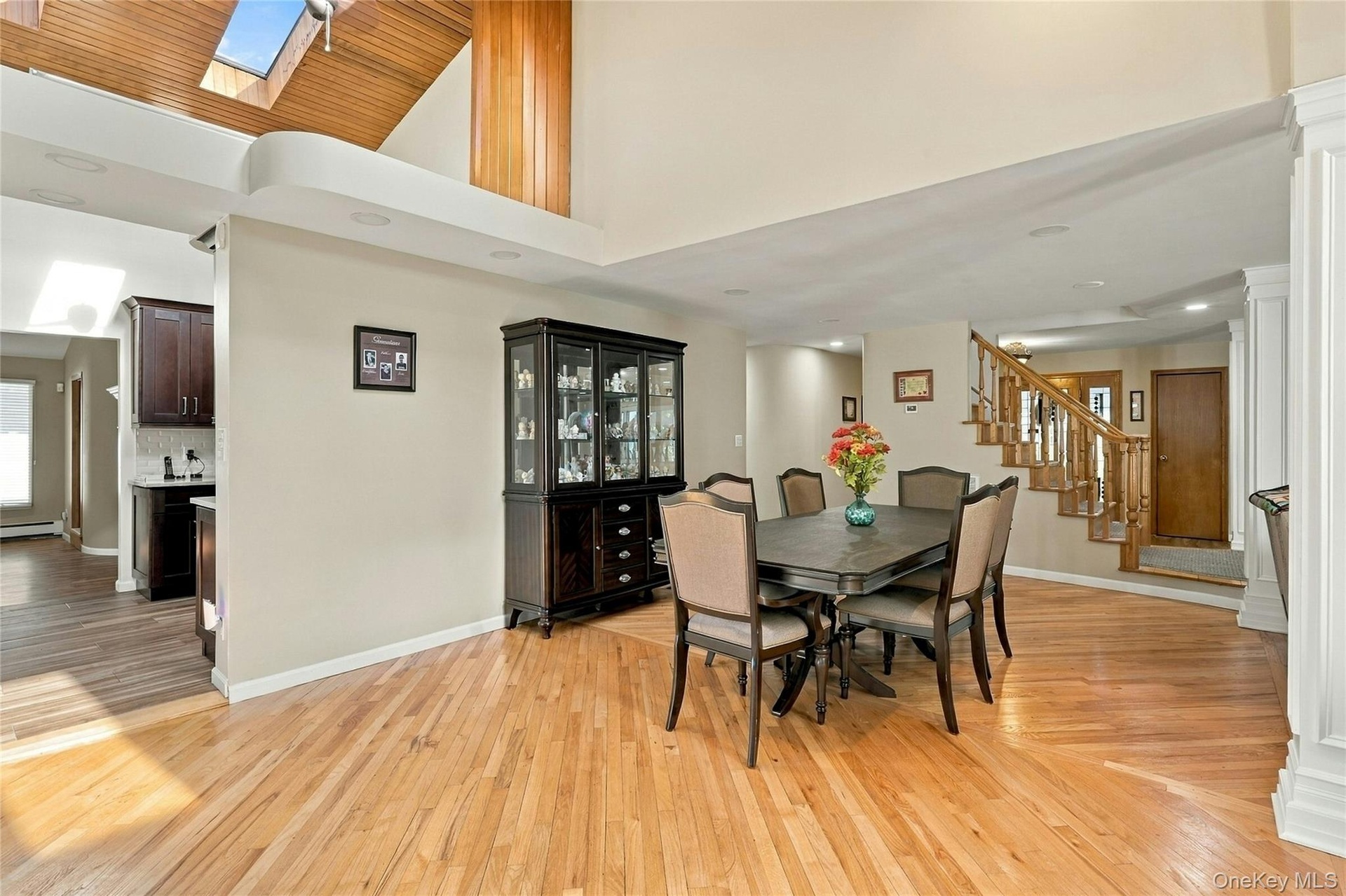 Vaulted ceilings with wood-plank detailing, recessed lighting, skylight, wood-finish flooring, and a staircase with decorative wood railings