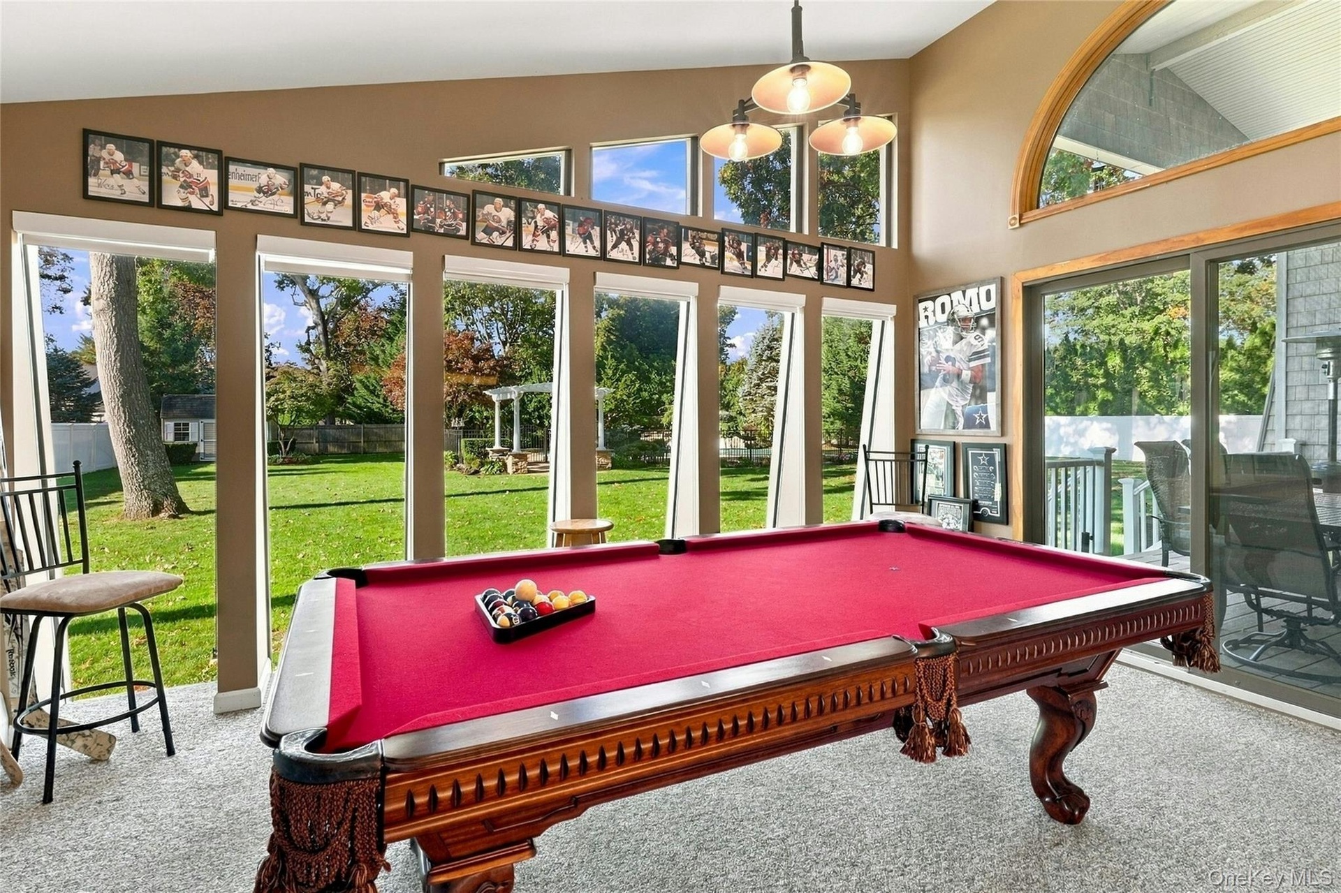 Vaulted ceiling with a multi-light fixture, expansive floor-to-ceiling windows, and sliding glass doors
