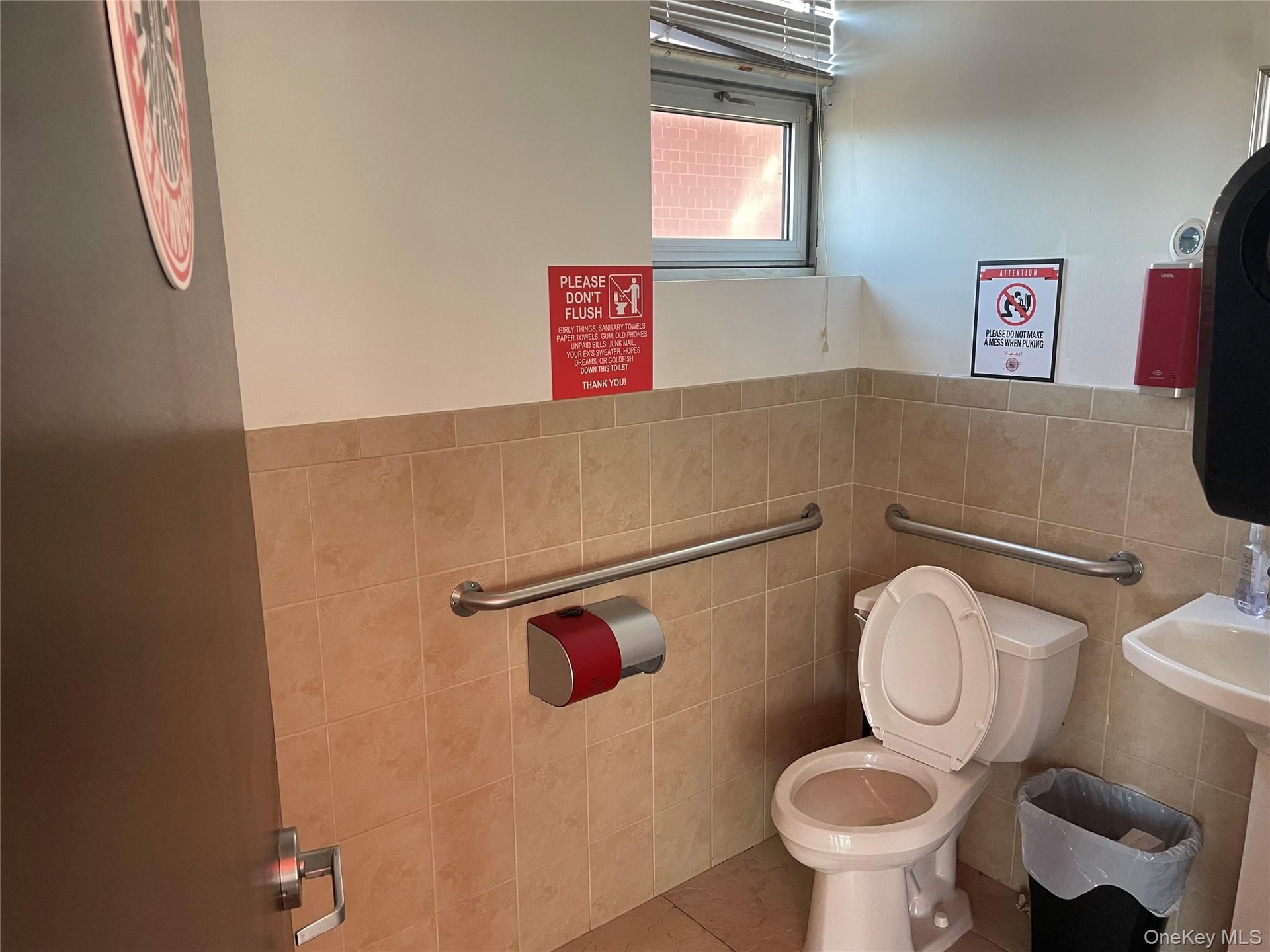 Bathroom featuring tile patterned floors, toilet, and tile walls