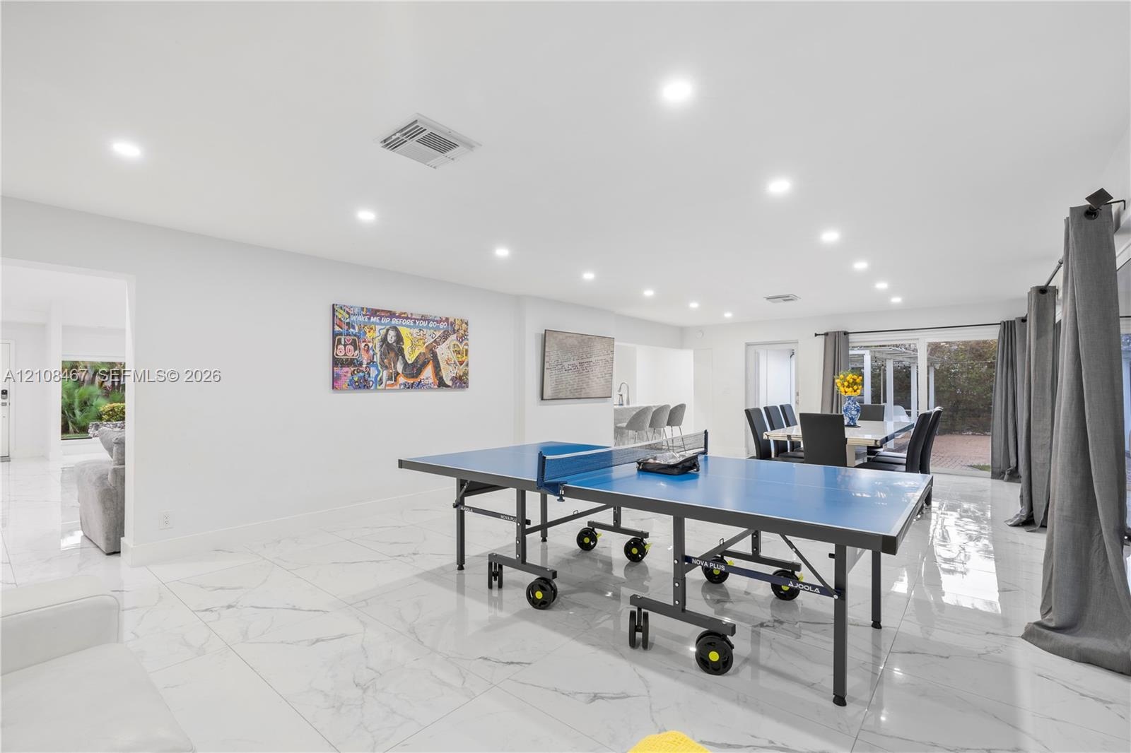 Large-format stone-style tile flooring, recessed ceiling lighting, and sliding glass door access