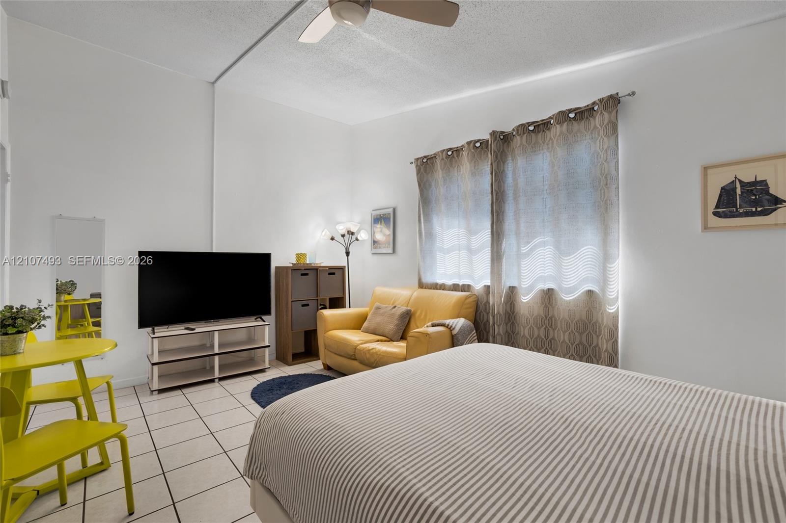 Interior space featuring white walls, light-toned ceramic tile flooring, and a ceiling-mounted light fixture with integrated fan