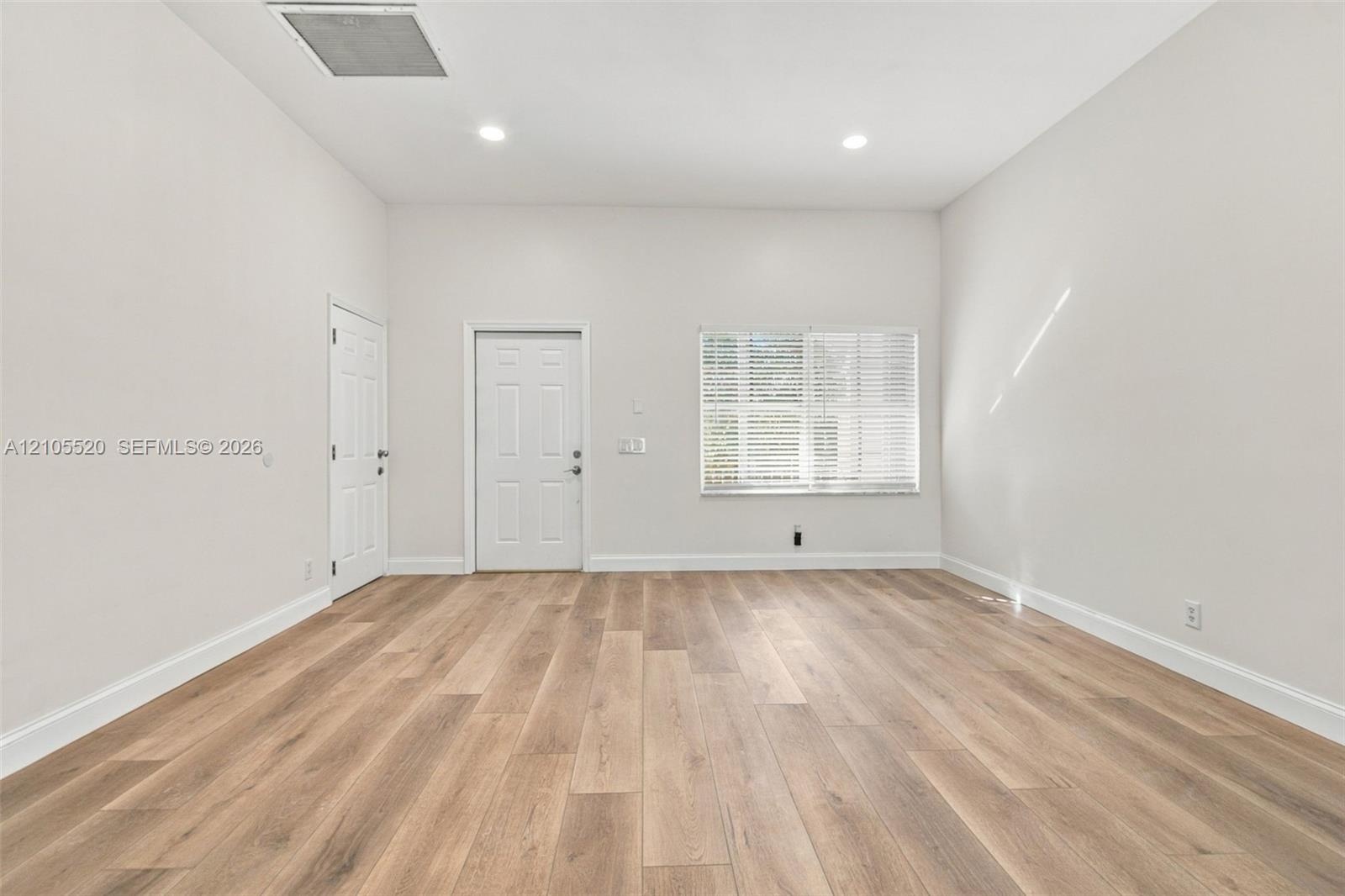 Neutral interior featuring wood-finish flooring, recessed lighting, and a multi-pane window with blinds