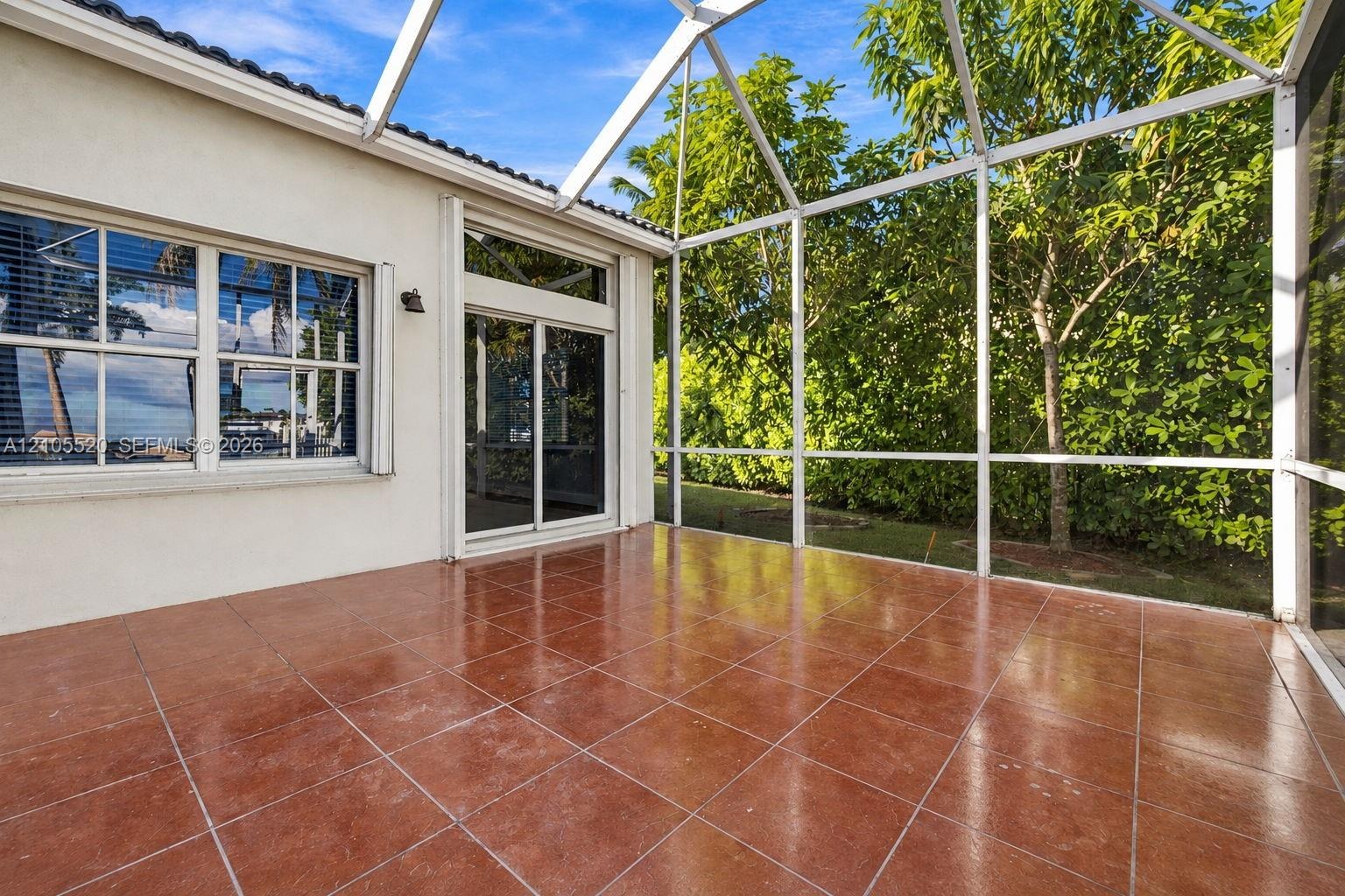 Screened-in patio featuring tile flooring, aluminum framing, a sliding glass door, and exterior sconce lighting