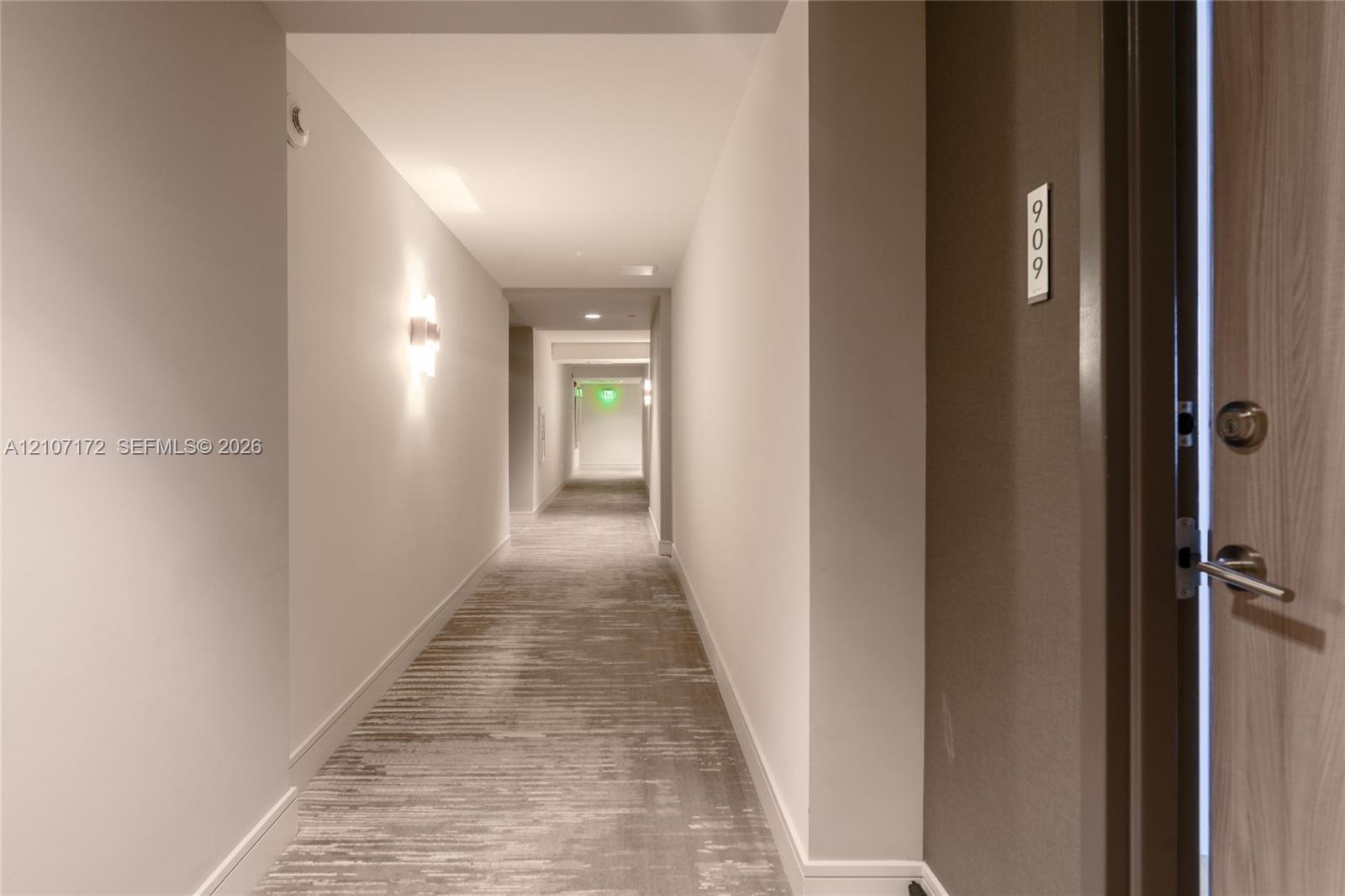 Lobby area featuring polished large-format stone-finish tile flooring, glass entry doors, recessed ceiling lighting, and a dark wood-trim architectura