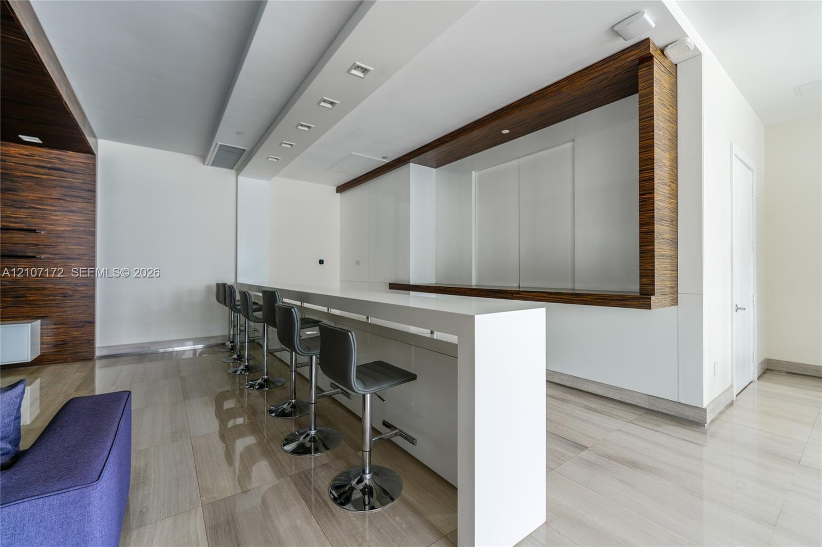 Open-concept interior featuring floor-to-ceiling glass wall panels, polished large-format tile flooring, and recessed ceiling lighting