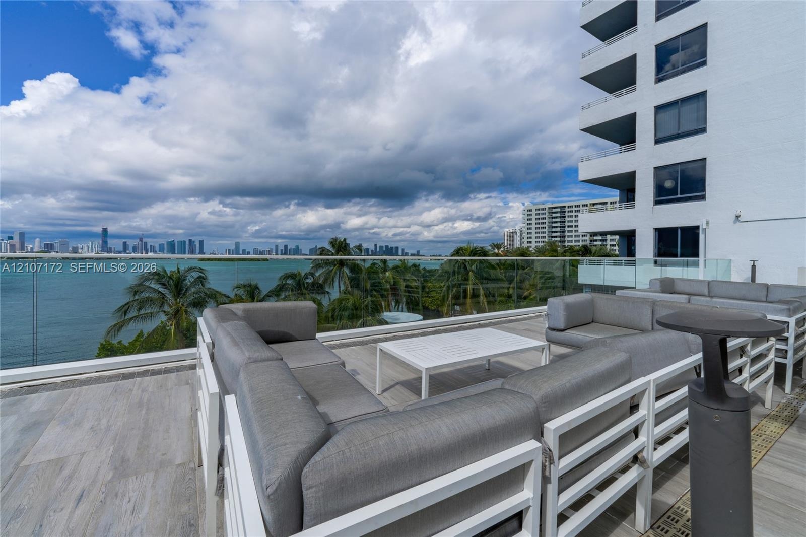 Waterfront patio featuring a paved stone terrace, glass panel railing, and cityscape backdrop