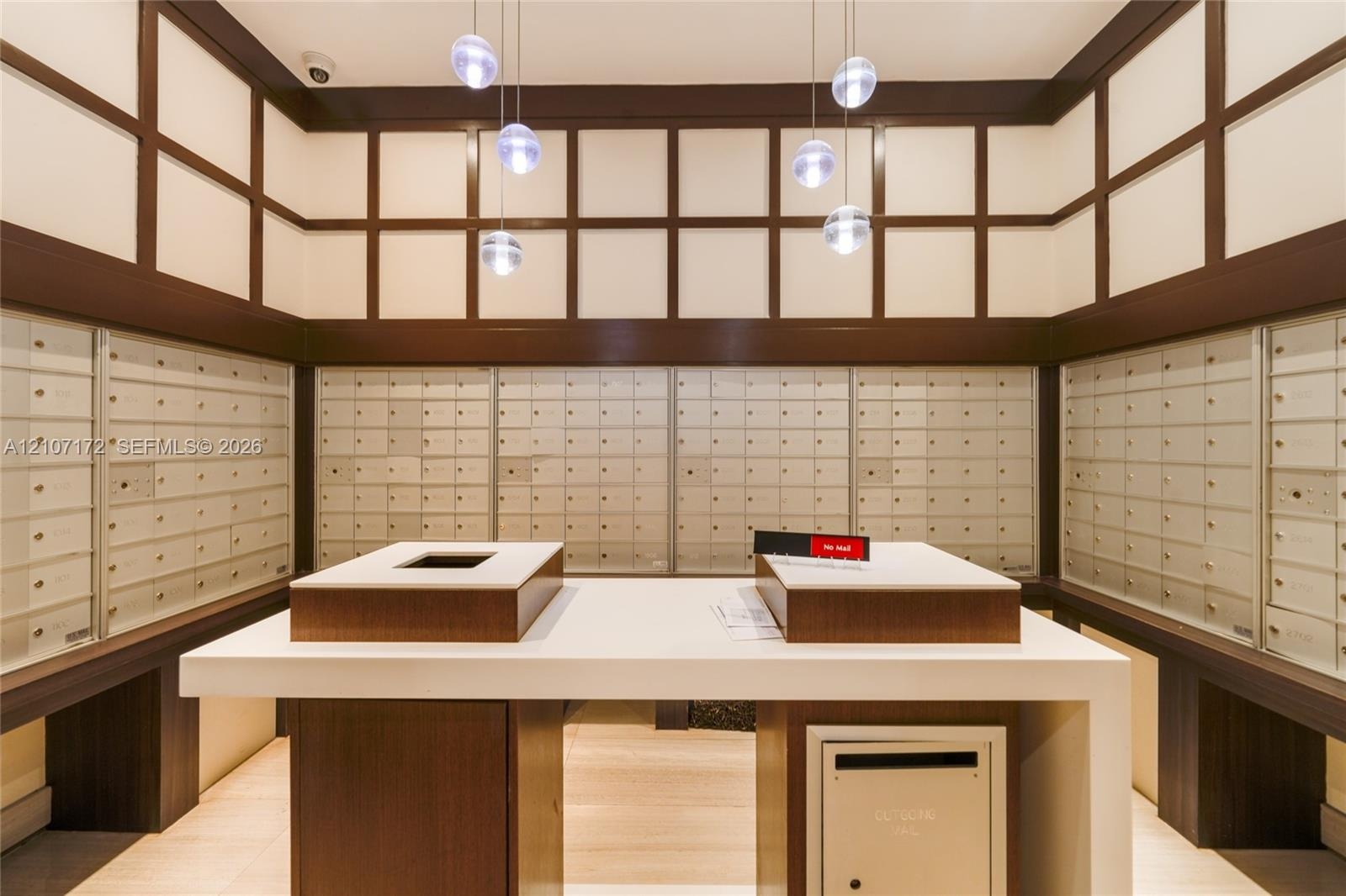 Custom built-in bar featuring a sleek waterfall edge countertop, integrated wood-finish cabinetry, recessed ceiling lighting, and polished stone floor