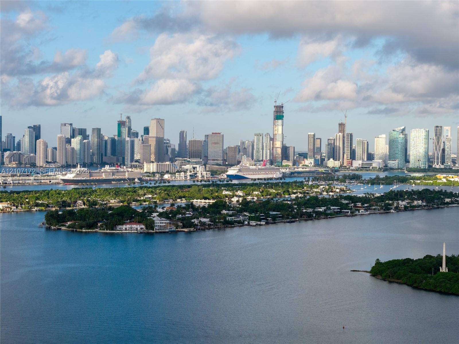 High-rise residential tower featuring white exterior cladding, recessed balconies, and an on-site tennis court, situated directly along the waterfront
