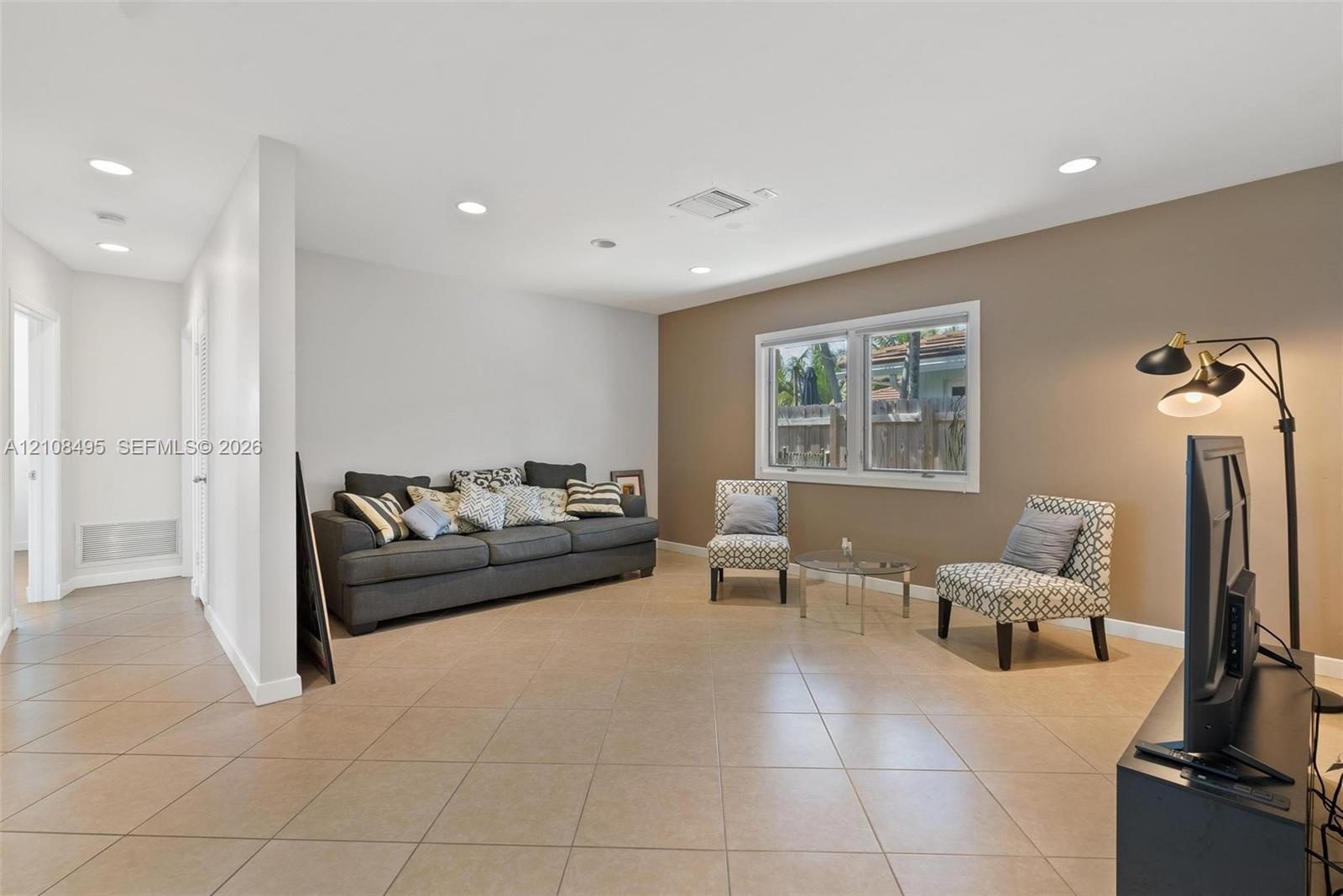 Open-concept interior featuring oversized tile flooring, recessed ceiling lighting, and large sliding glass windows