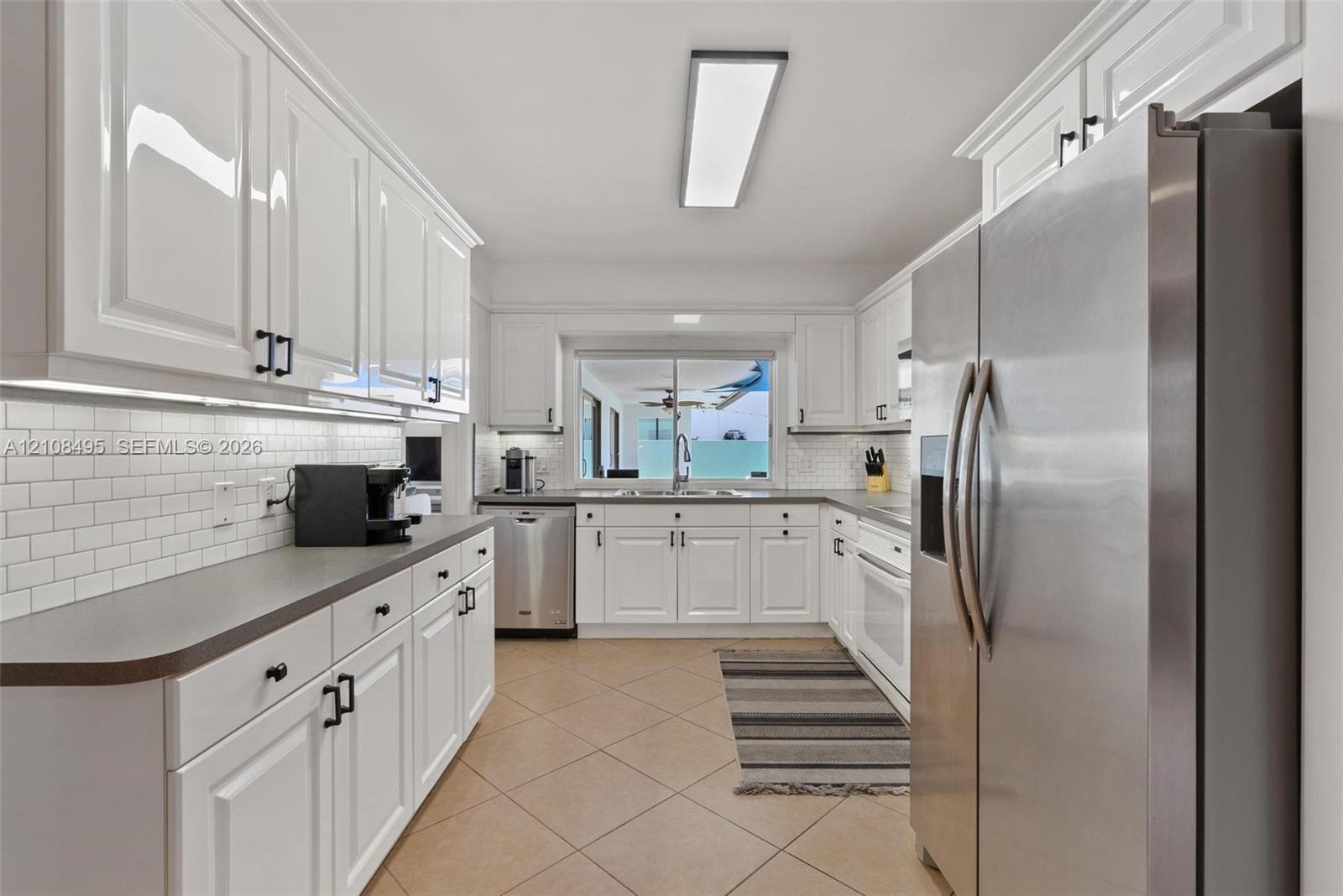 Open-concept living space featuring neutral ceramic tile flooring, recessed lighting, and large glass sliding doors