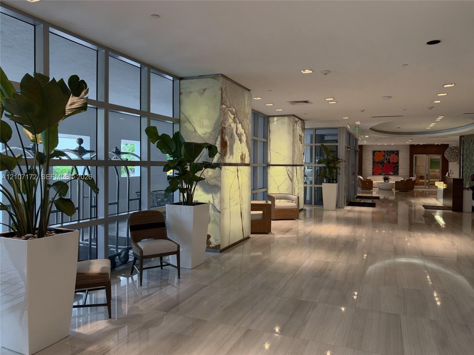 Floor-to-ceiling dark wood-finish paneling with integrated wall shelving, white lacquer built-in cabinetry, polished stone flooring, and a sleek break
