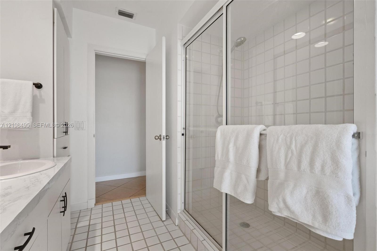 Entryway featuring a built-in wood-finish display shelf, recessed ceiling lighting, tile flooring, and vertical blinds