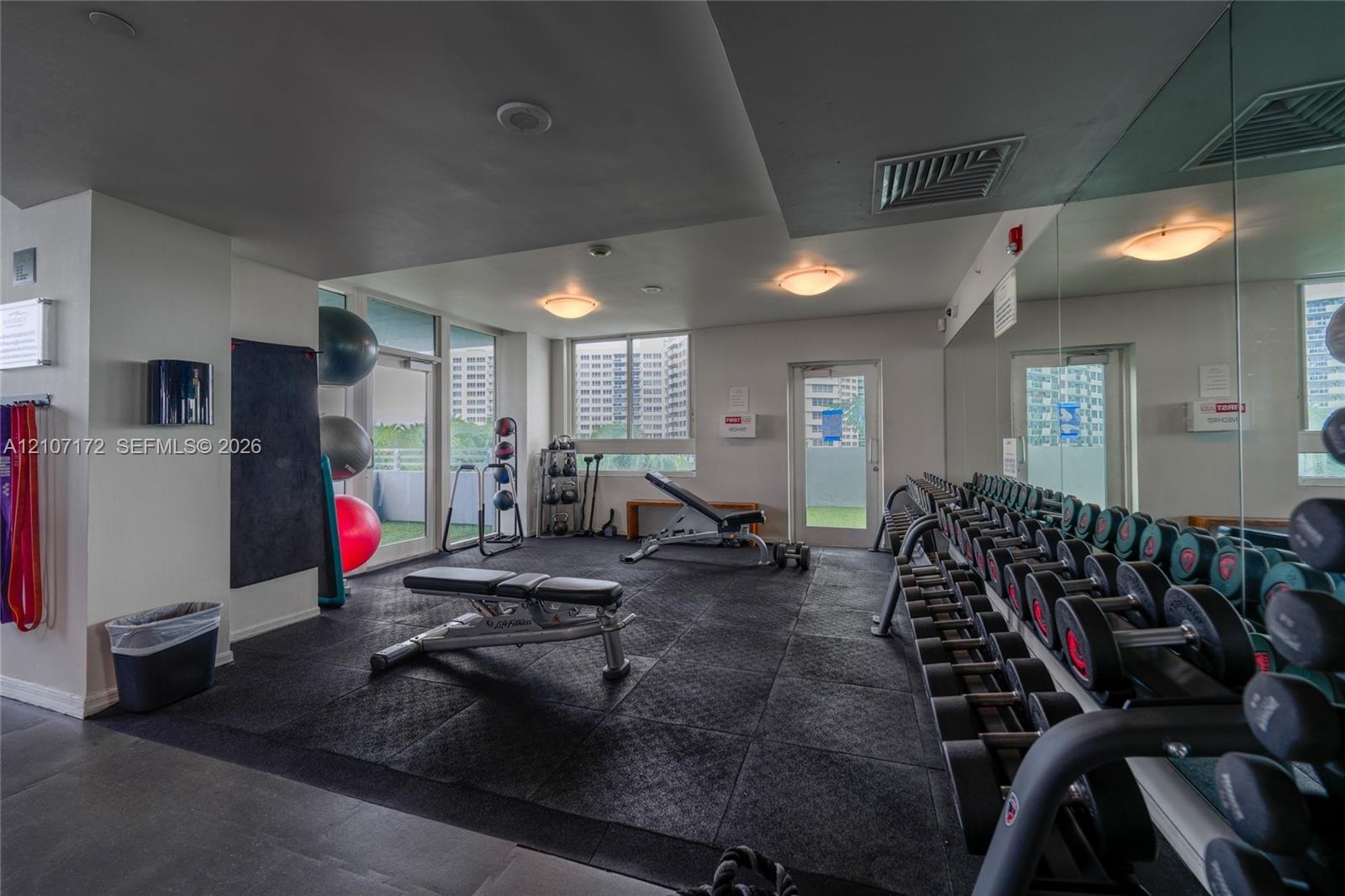 Fitness center featuring tile flooring, ceiling-mounted lighting, and floor-to-ceiling windows with access to an exterior terrace