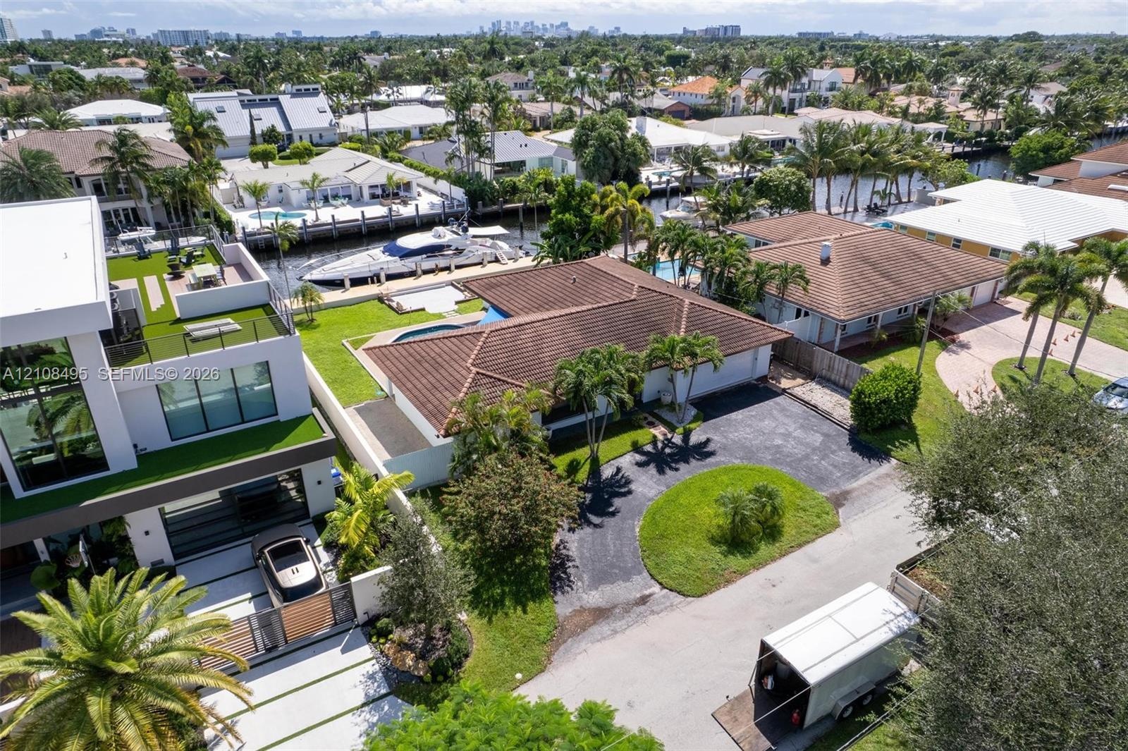 Aerial view of a waterfront property featuring a private boat dock, a swimming pool, a tiled roof, and a paved driveway