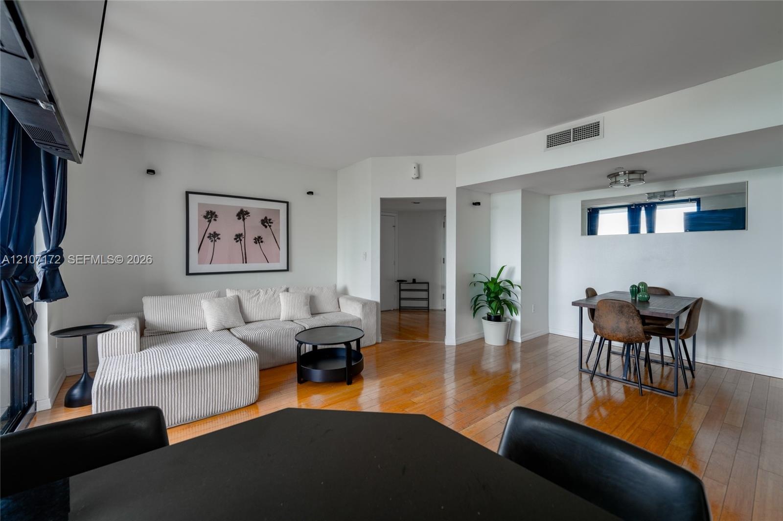 Open floor plan featuring wood-finish flooring, recessed wall lighting, and a mirrored wall accent
