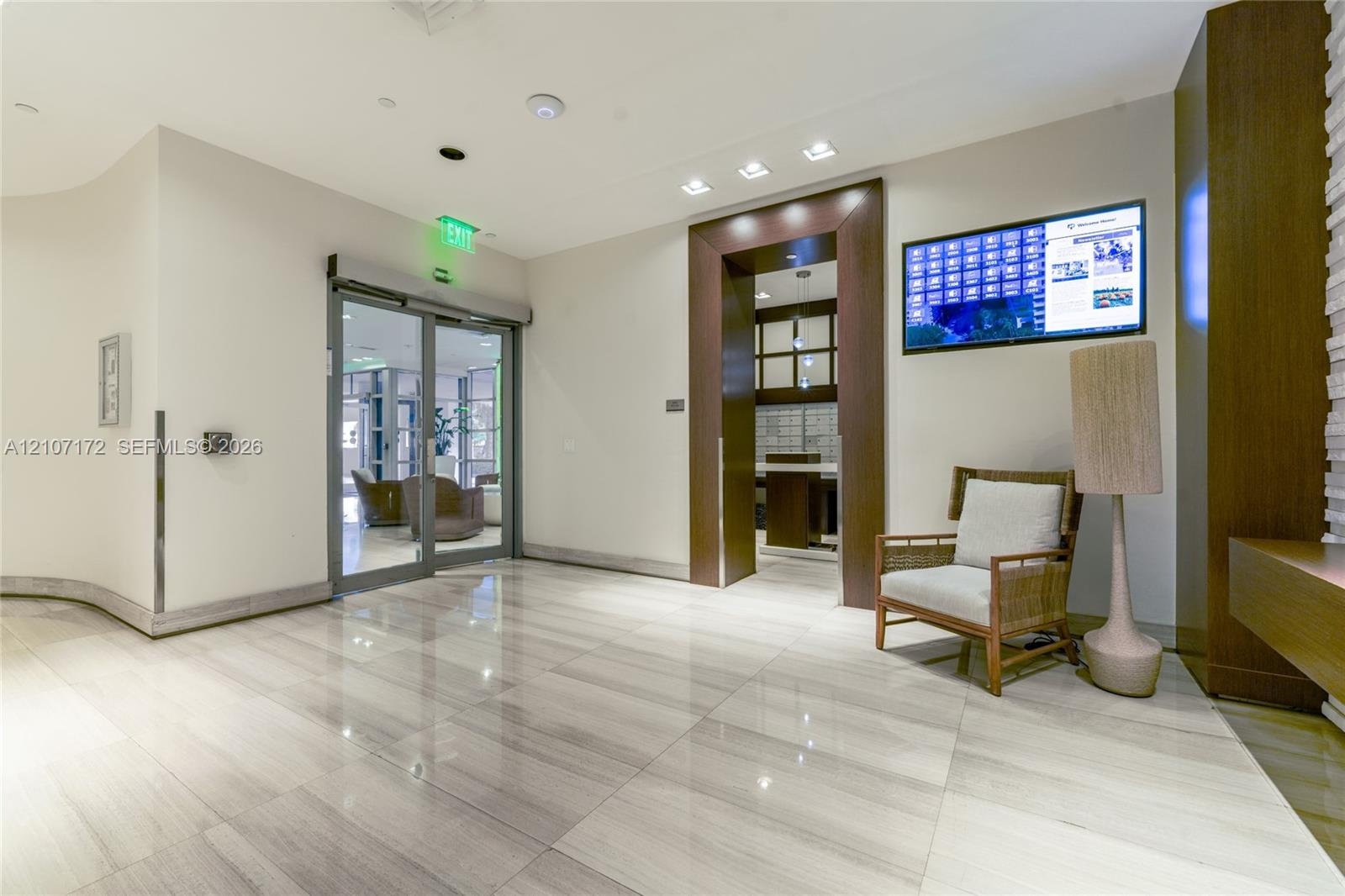 Lobby interior featuring full-height glass windows, backlit stone-clad pillars, polished stone flooring, and recessed ceiling lighting
