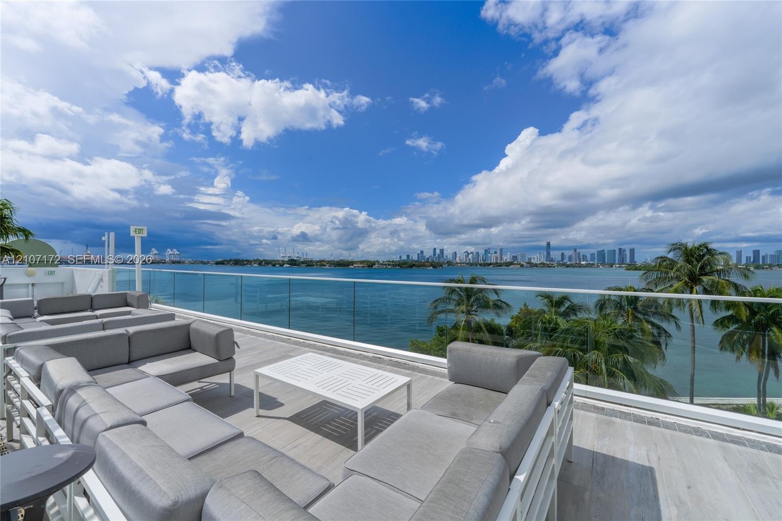 Expansive private terrace featuring large-format porcelain tile flooring and a frameless glass balustrade overlooking the water and metropolitan skyli