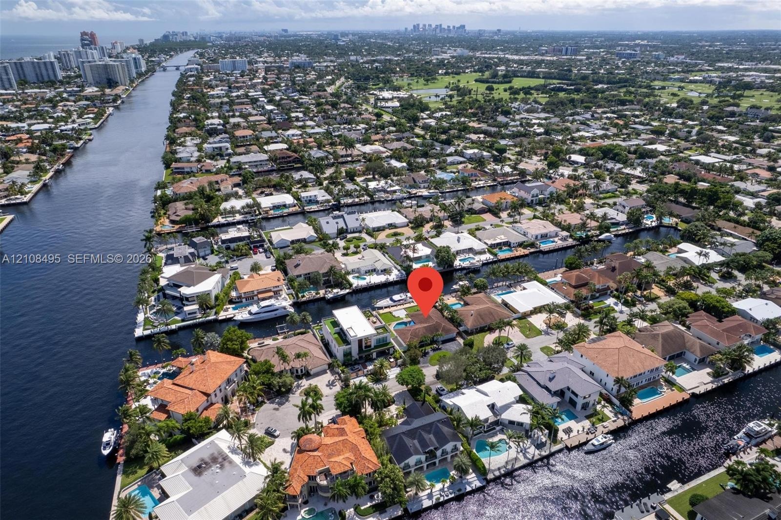Waterfront property featuring a tile roof, paved driveway, swimming pool, and private boat dock