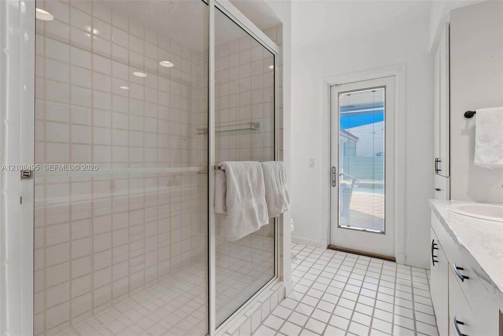 Open-concept interior featuring large-format tile flooring, recessed lighting, and multiple sliding glass doors providing outdoor access