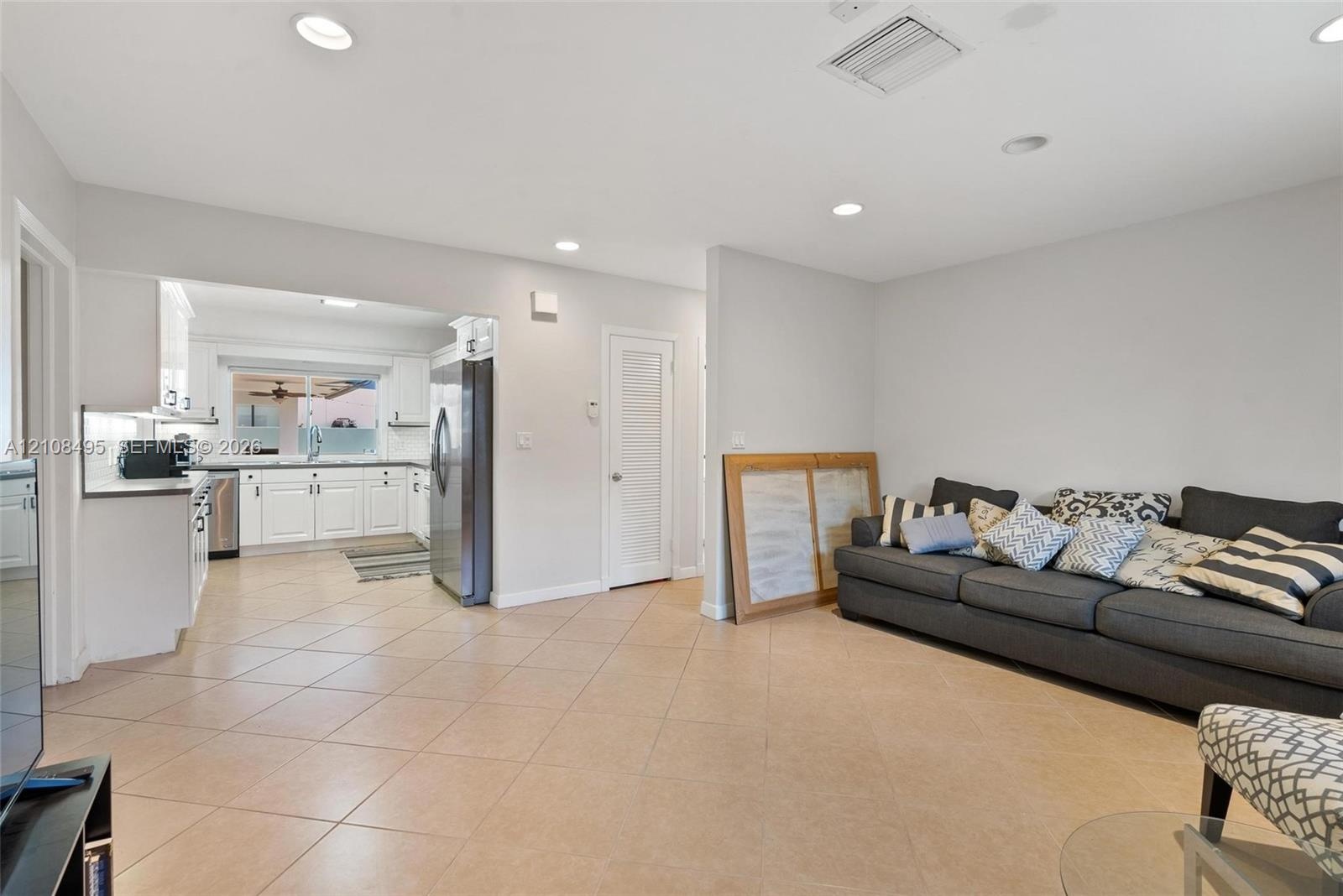 Open-concept living space featuring large-format ceramic tile flooring, expansive floor-to-ceiling windows, and recessed lighting
