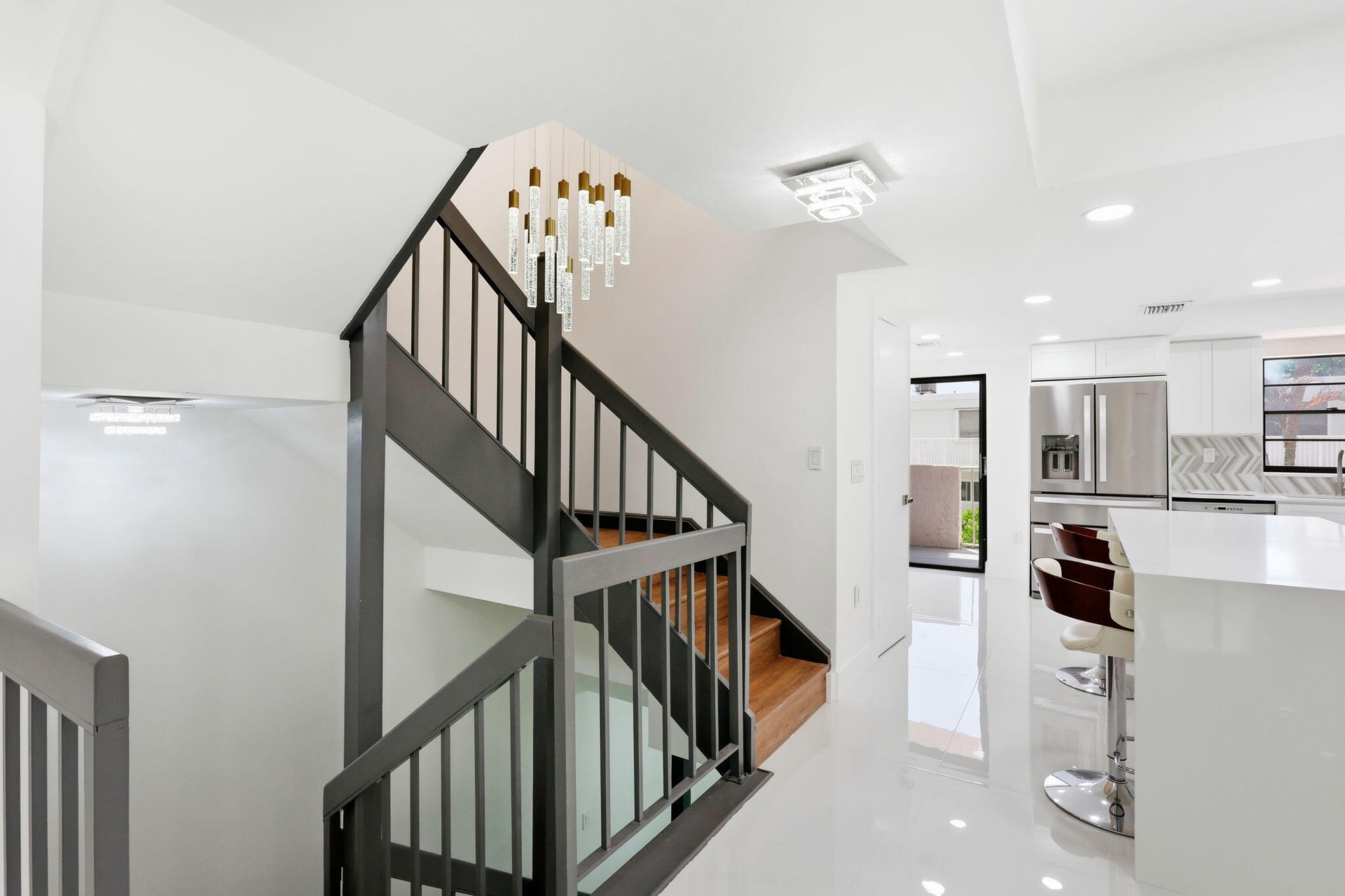 Modern kitchen featuring stainless steel appliances, white cabinetry, and beatifyl staircase