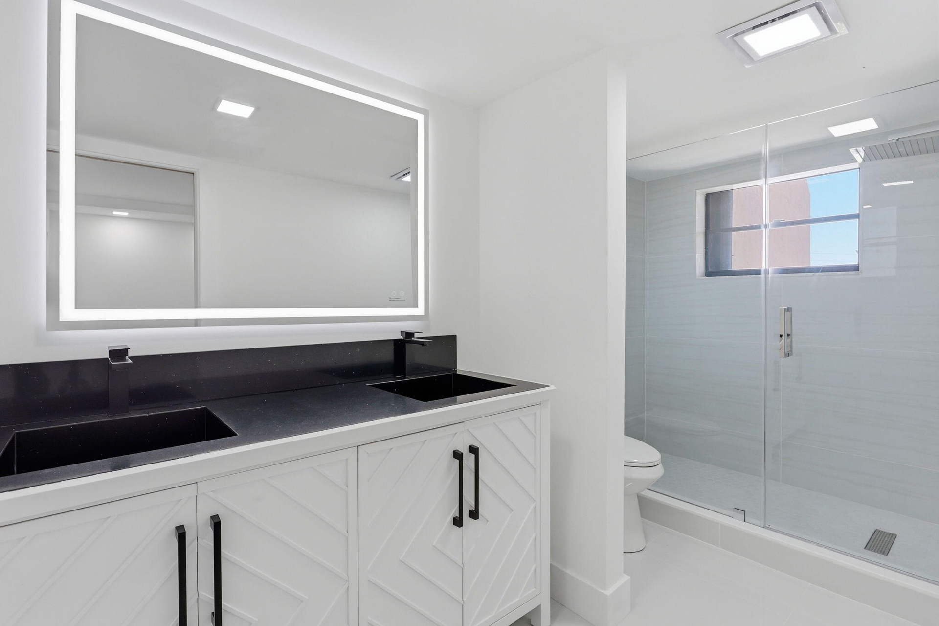 Dual vanity with integrated sinks, black countertop, and white cabinetry
