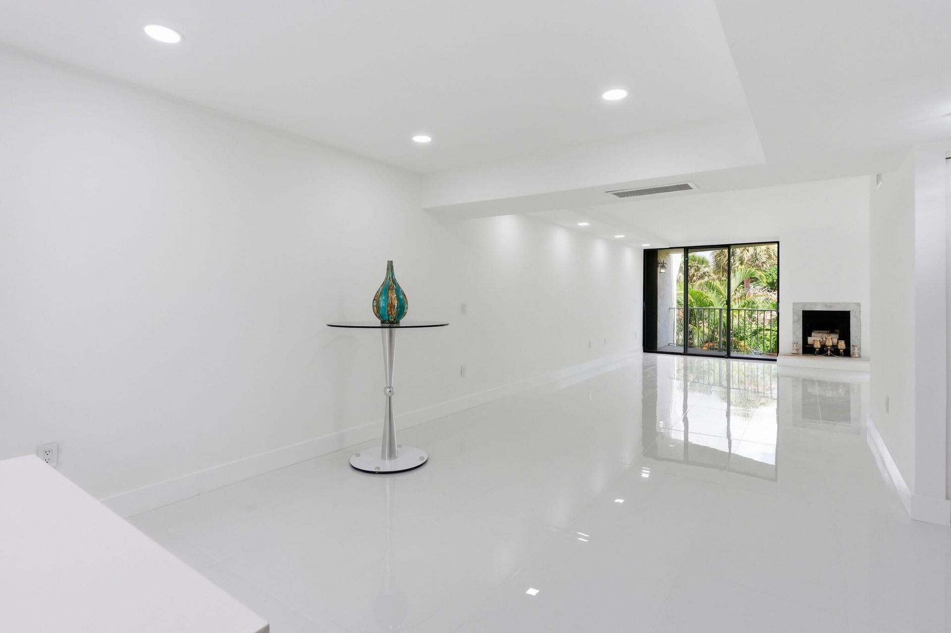 Recessed lighting, polished tile flooring, white walls, and a fireplace with a stone surround