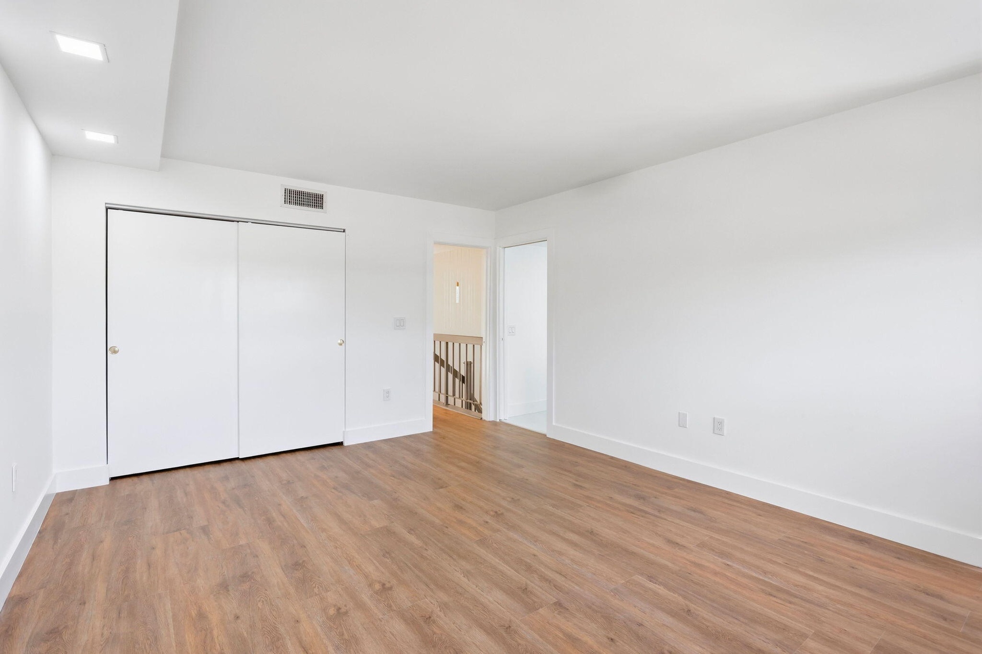 Spacious interior with wood-finish flooring, recessed lighting, and white walls