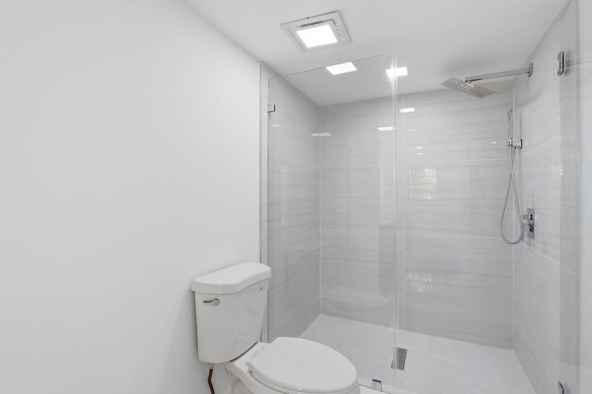 Walk-in shower with clear glass enclosure, tiled walls, and a rainfall showerhead