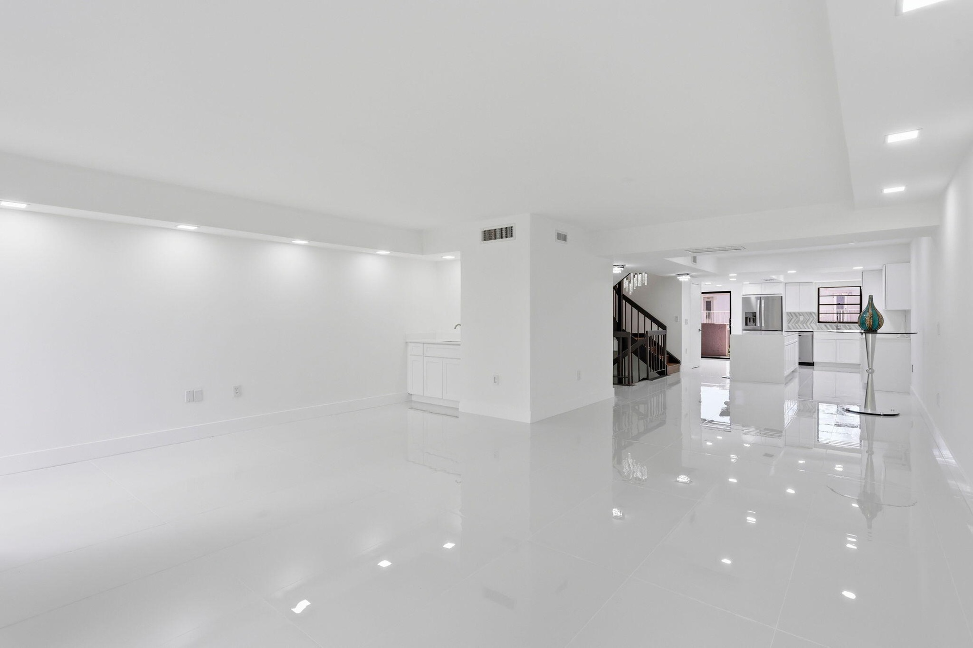 Open-concept living space featuring high-gloss tile flooring, recessed lighting, and a white cabinet with a sink