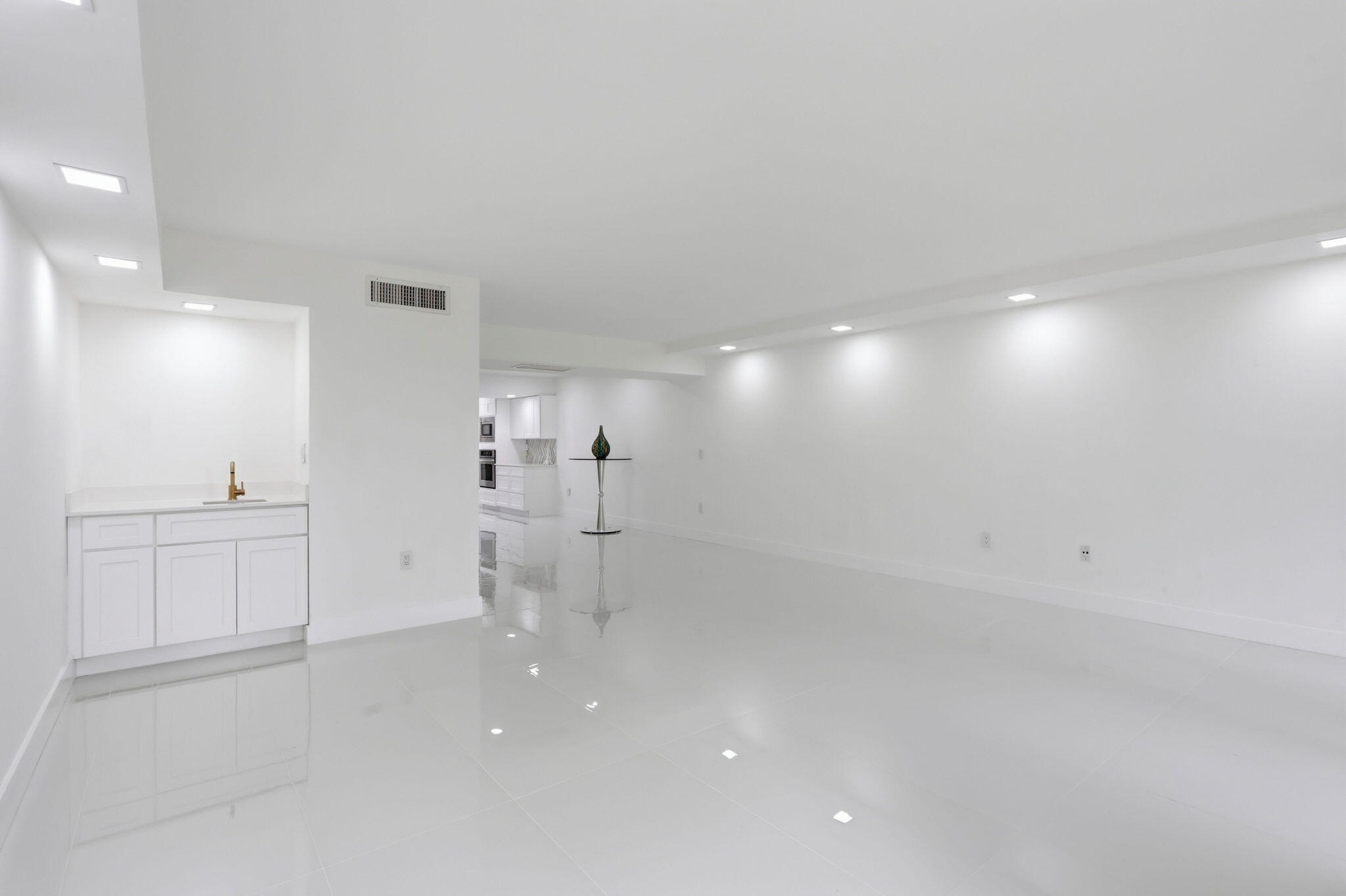 Expansive room featuring glossy tile flooring, recessed lighting, and a built-in wet bar with white cabinetry and a light-toned countertop