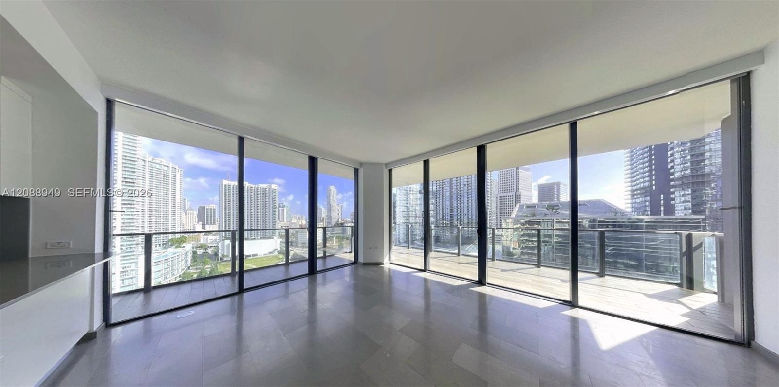 Floor-to-ceiling glass walls, expansive wraparound balcony with glass railing, and large-format tile flooring