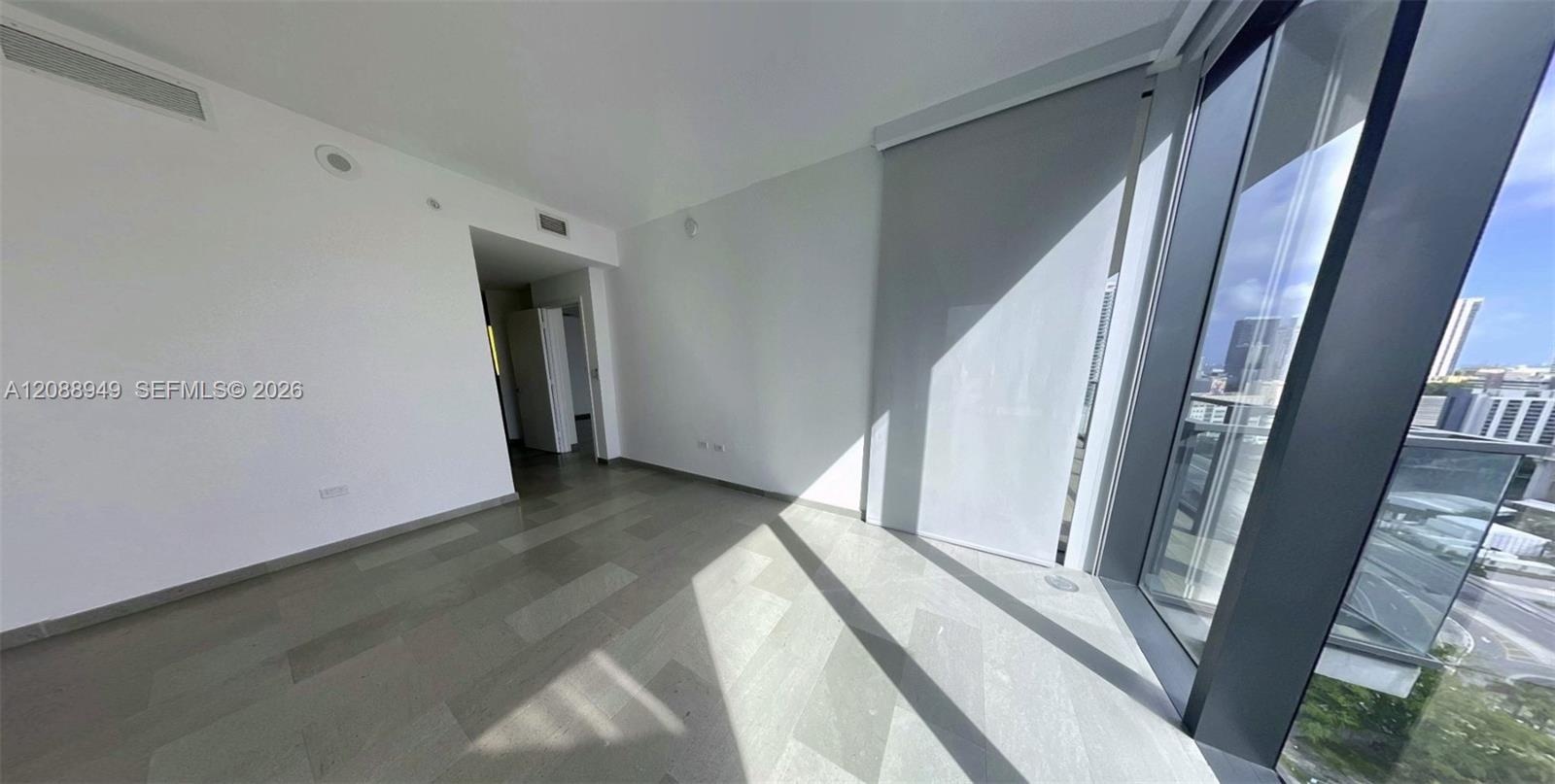 Floor-to-ceiling glass windows, neutral wood-finish flooring, and recessed ceiling lighting