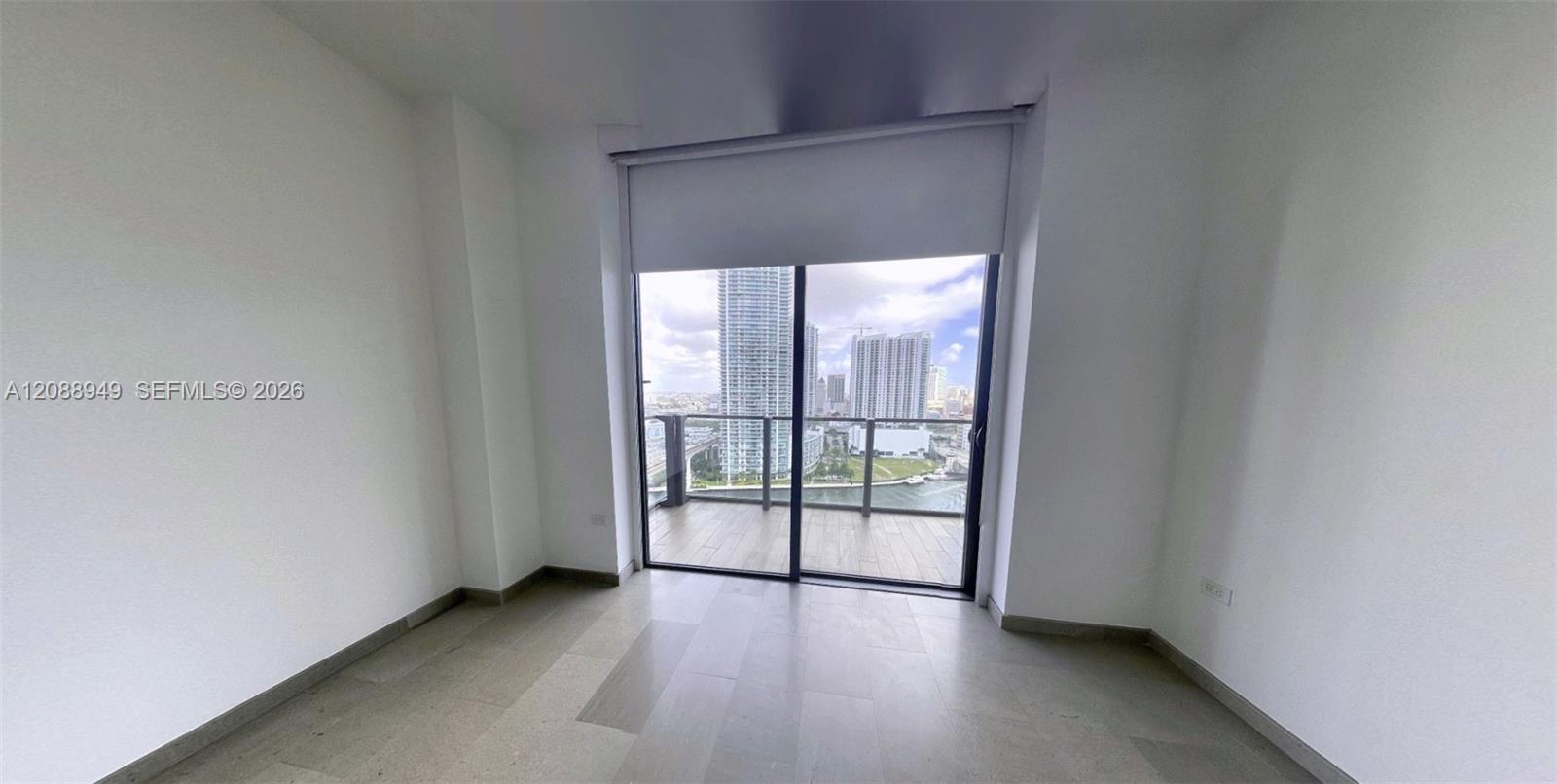 Room featuring large-format tile flooring, floor-to-ceiling sliding glass doors, and a private balcony with metal railings